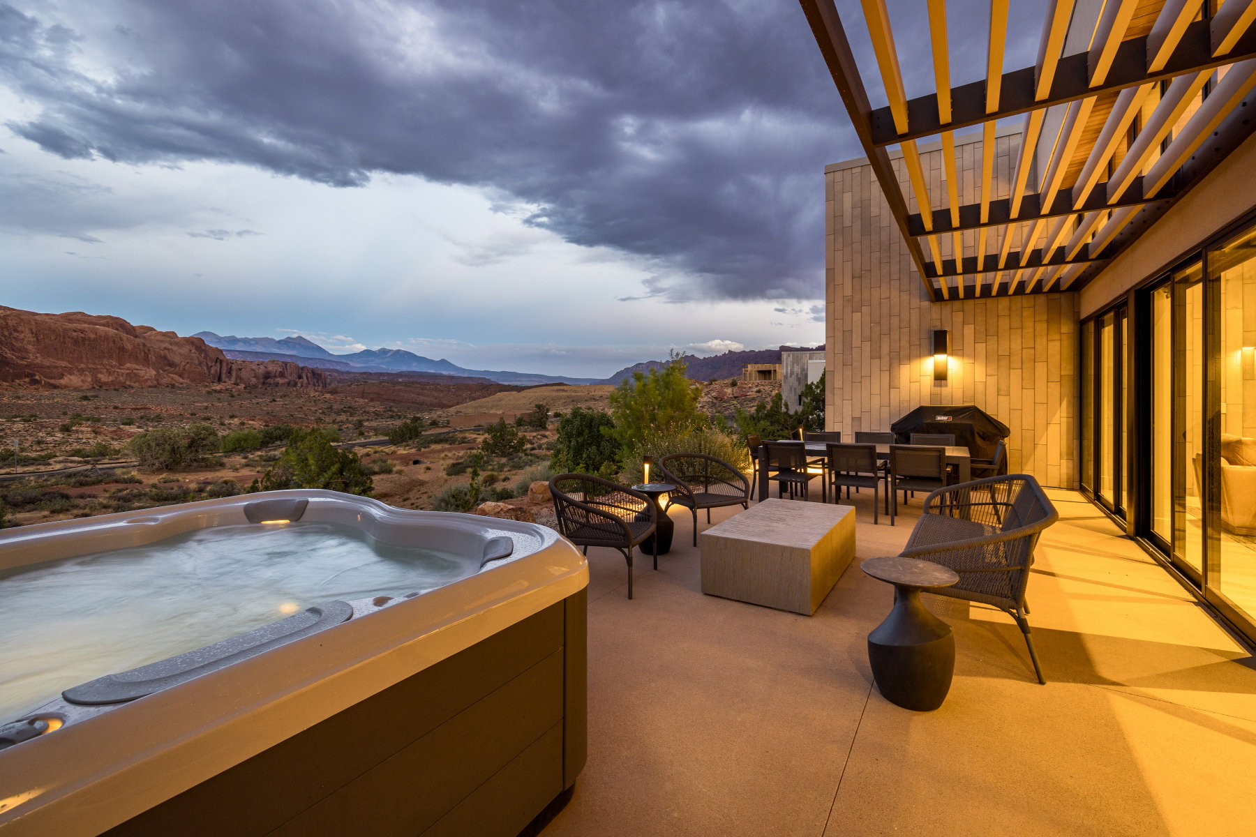 Spacious outdoor patio featuring a built-in spa, slatted pergola, and expansive desert landscape