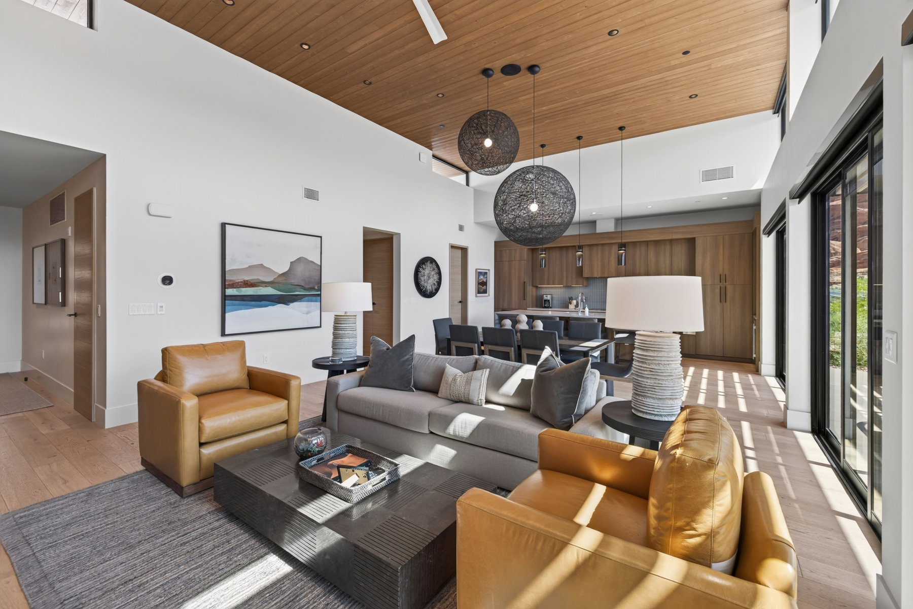 Open-concept living space with a wood-finish ceiling, light wood-finish flooring, and high ceilings