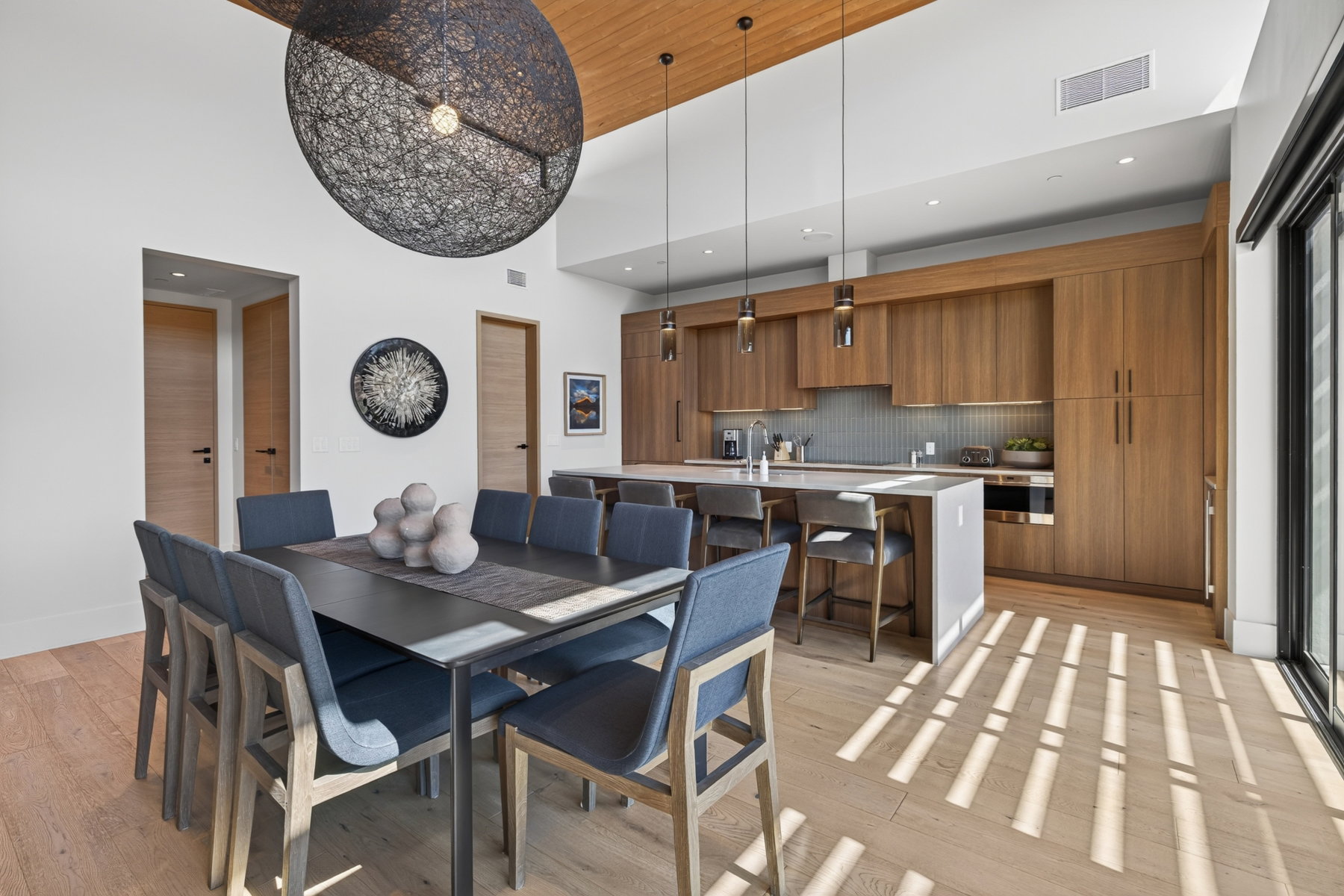 Open-concept living space featuring wood-finish flooring, a kitchen with flat-panel wood cabinetry, and a central island with bar seating