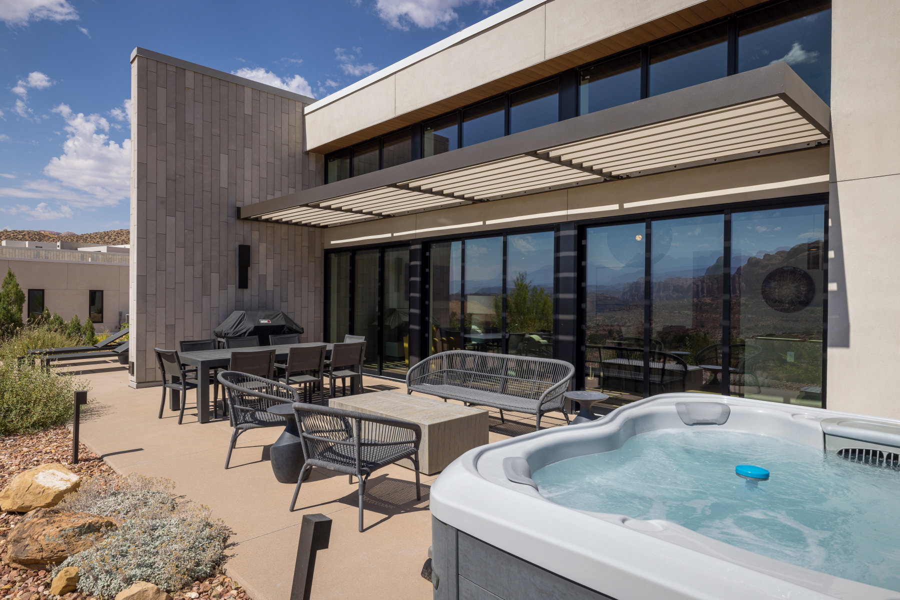 Outdoor patio featuring a built-in hot tub, concrete paving, and a slatted pergola