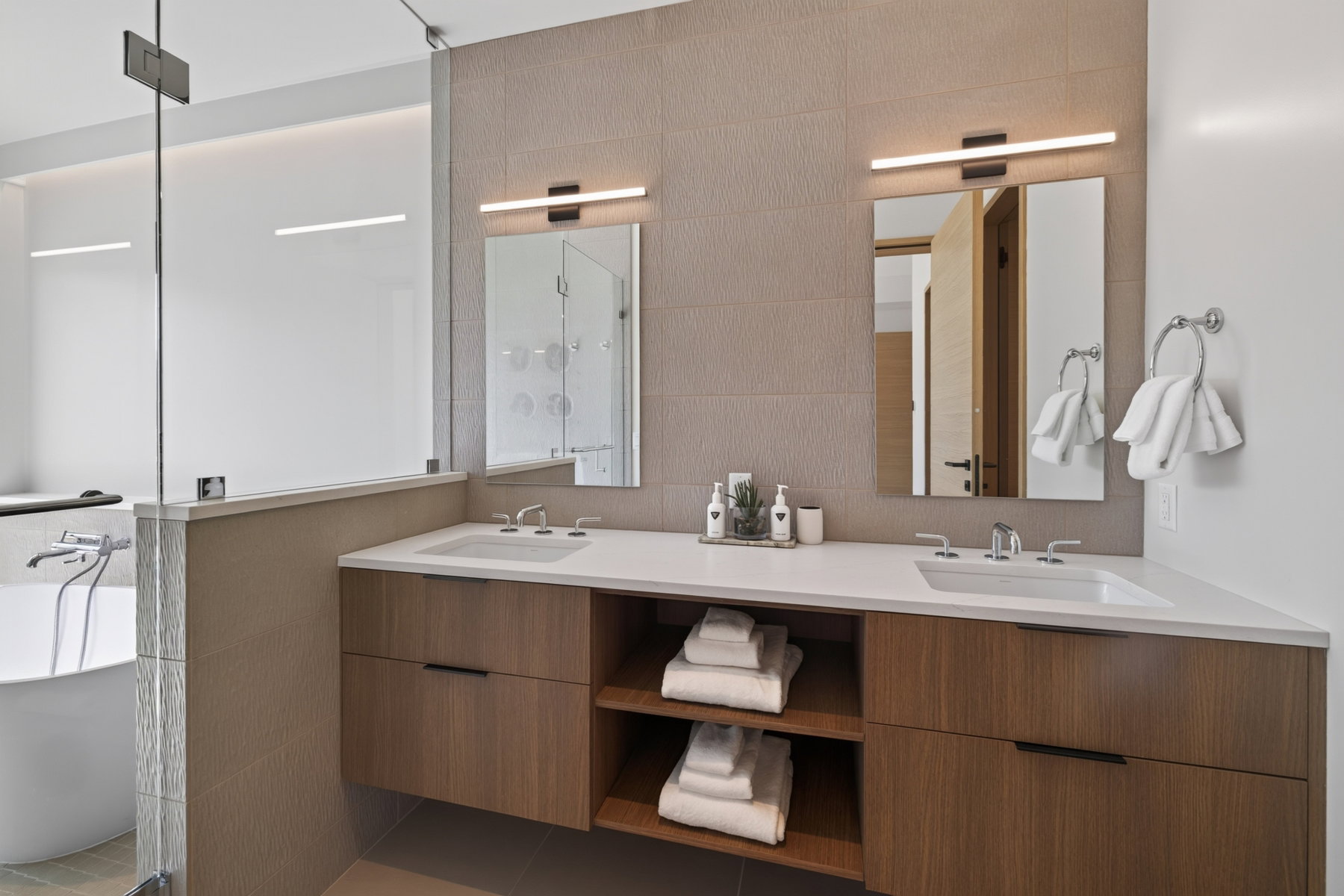 Contemporary bathroom featuring a floating dual-sink vanity with wood-finish cabinetry and white countertops