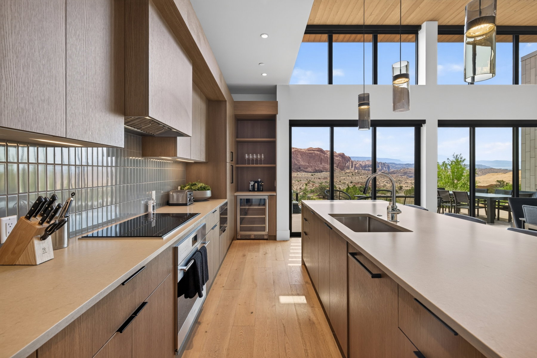 Gourmet kitchen featuring a large island with an undermount sink, built-in cooktop, and light wood-finish cabinetry