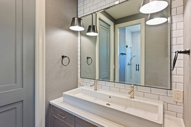 Bathroom vanity featuring a dual vessel sink, gold-finish faucets, and a full-width mirror