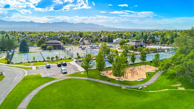 Expansive green spaces featuring a playground, multiple tennis courts, and a community building