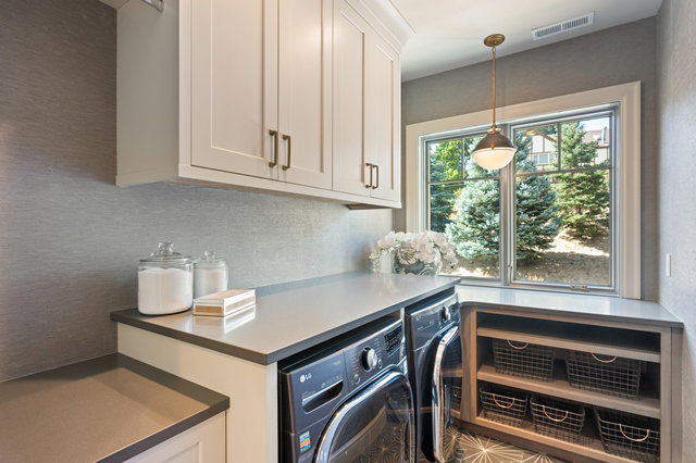 Dedicated laundry area featuring white shaker-style cabinetry, a built-in countertop, and a window providing natural illumination