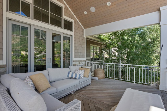 Spacious covered deck featuring wood-finish flooring, a white metal railing, and a tongue-and-groove ceiling with recessed lighting