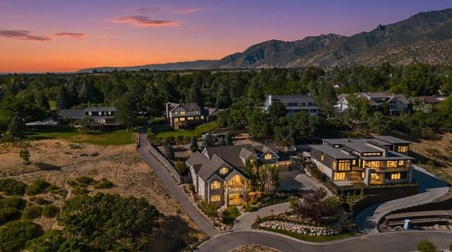 Gated community featuring a paved street, mature landscaping, and mountain backdrop