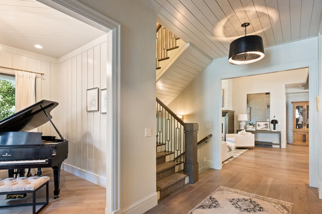 Entryway featuring hardwood flooring, an open staircase with metal balusters, and a paneled ceiling with a decorative pendant light