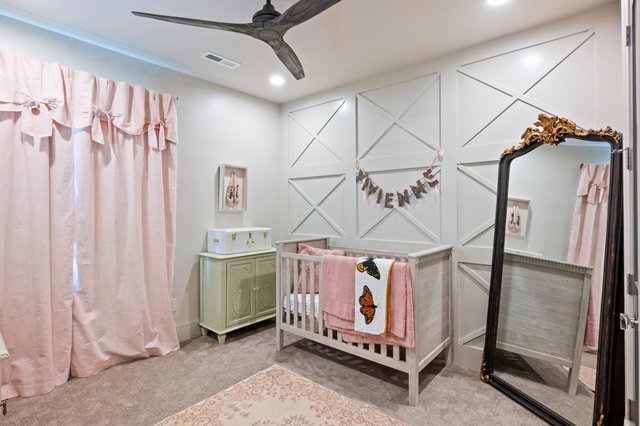 Recessed ceiling lighting illuminates the room, featuring a modern ceiling fan and decorative wainscoting on the far wall