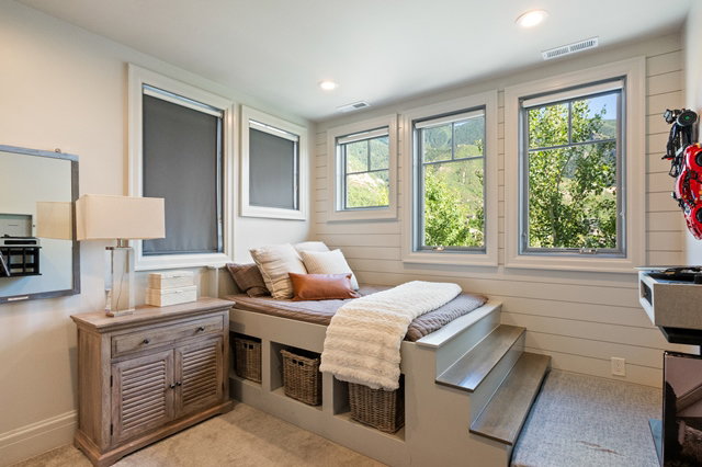 Built-in platform bed with integrated storage, wood-finish steps, multiple windows, recessed lighting, and shiplap wall detailing