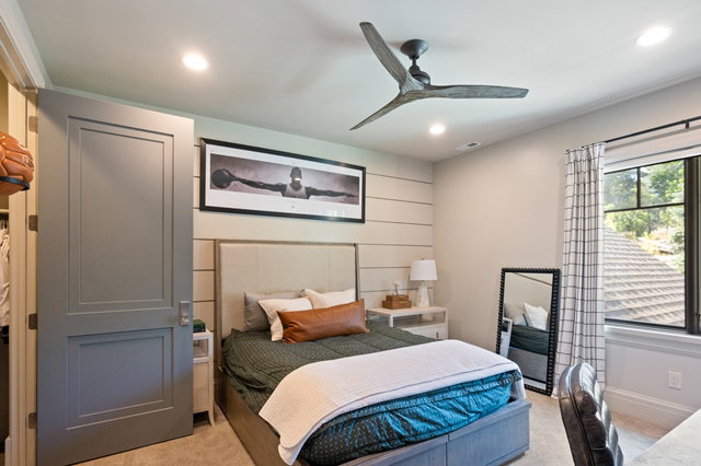 Recessed lighting and ceiling fan in a room featuring a window with black trim, a paneled accent wall, and a two-panel interior door