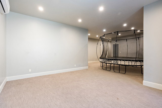 Spacious room featuring light-colored carpet, recessed ceiling lighting, and a mini-split air conditioning unit