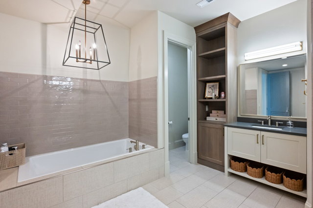 Bathroom featuring a built-in soaking tub, subway tile wainscoting, and a geometric chandelier