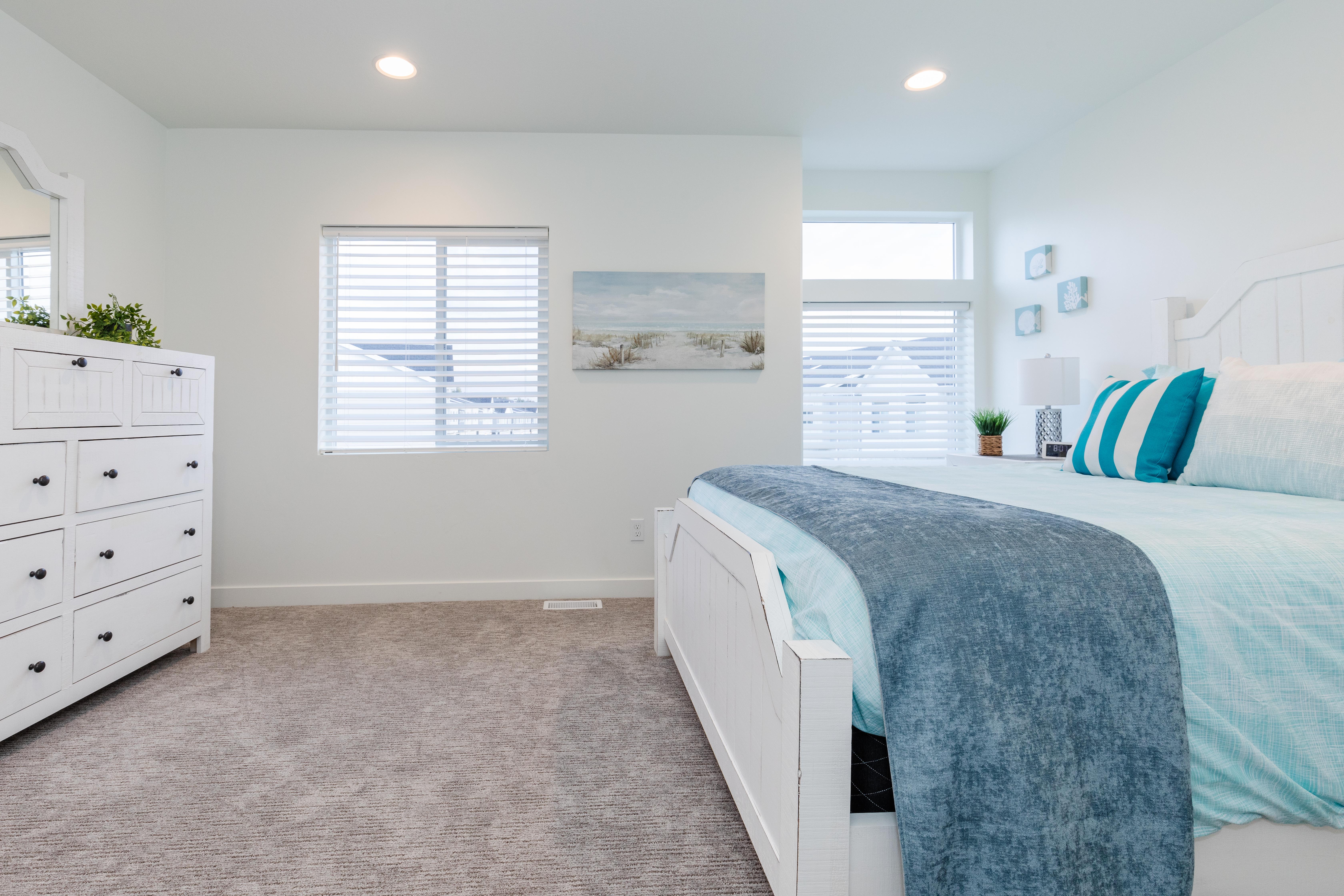 Carpeted bedroom featuring multiple windows with horizontal blinds, recessed lighting, and a white baseboard trim