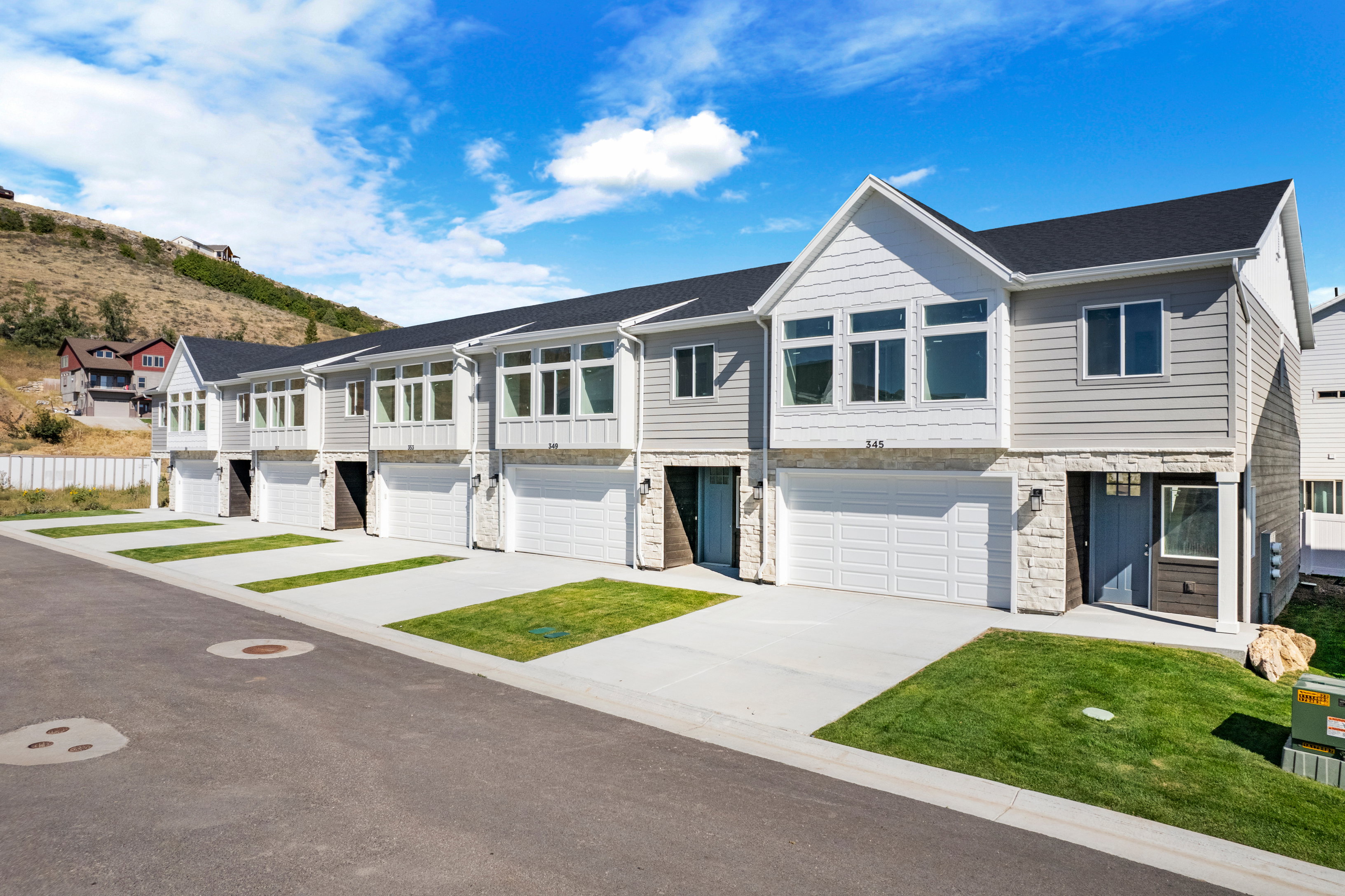 Contemporary townhome exteriors featuring light gray siding, white trim, and stone accents