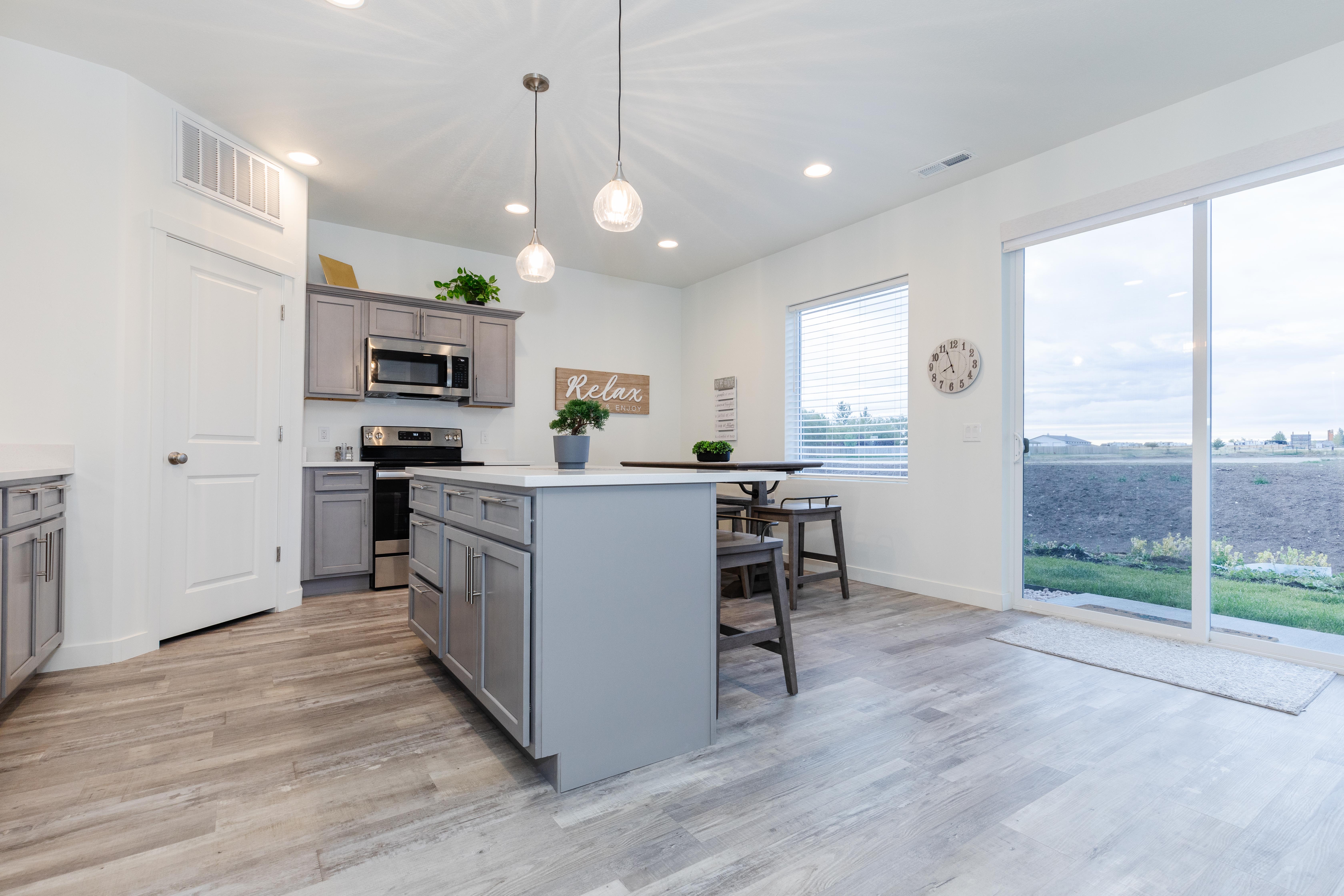 Kitchen featuring a central island with countertop seating, stainless steel appliances, grey cabinetry, and wood-finish flooring