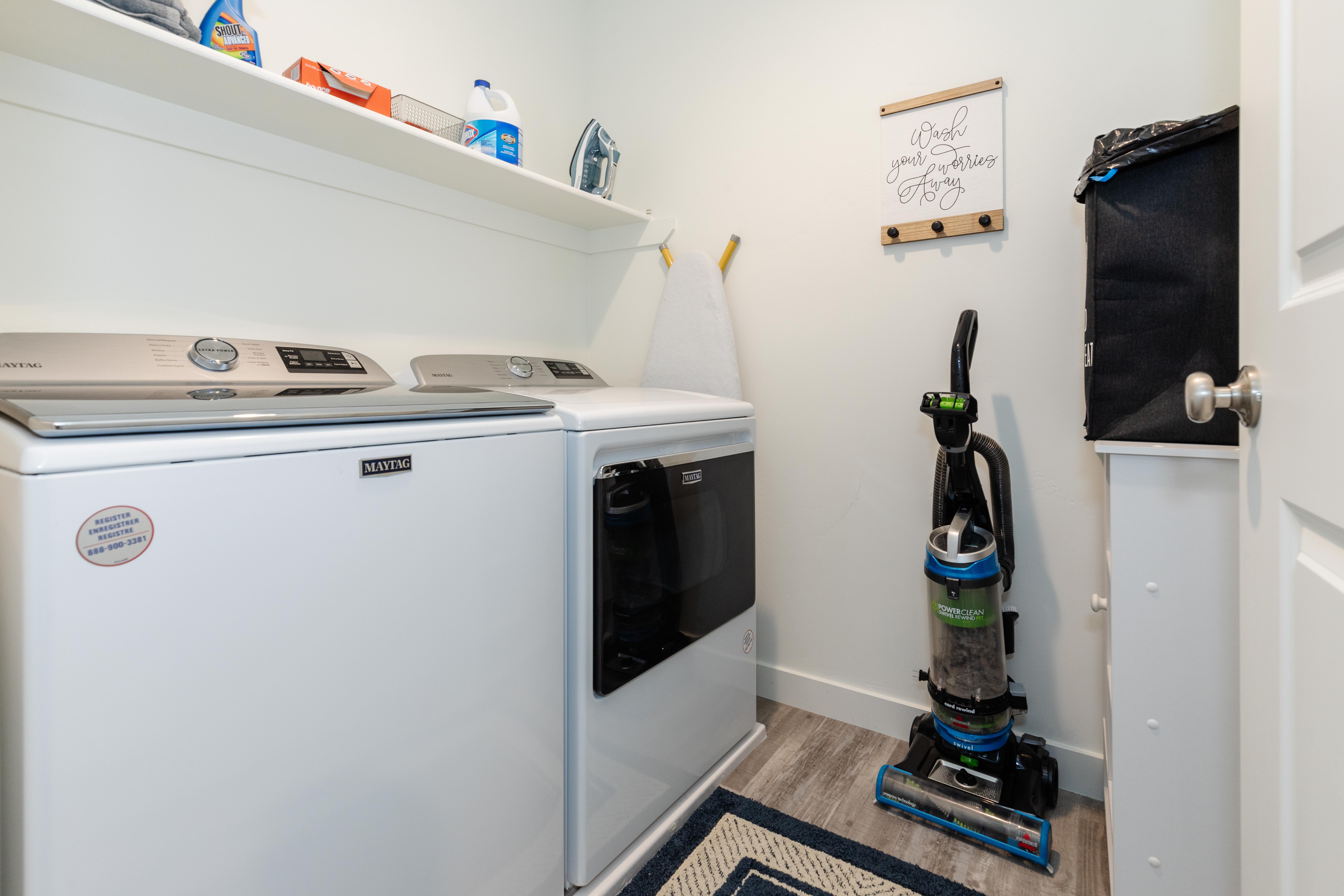 Dedicated laundry area featuring a built-in shelf, light wood-finish flooring, and crisp white walls