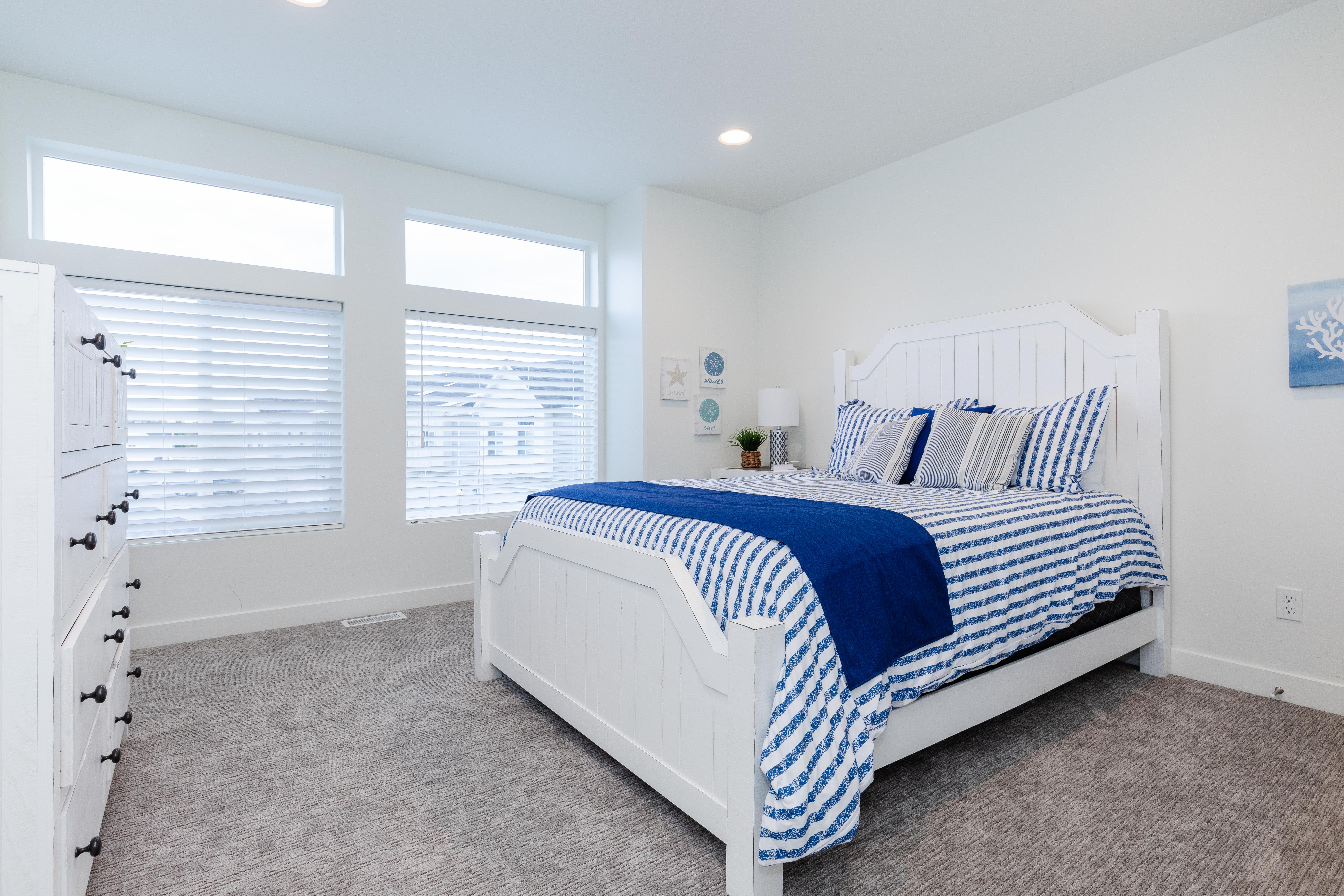 Bedroom featuring light gray carpet flooring, white walls, recessed lighting, and multiple windows with horizontal blinds