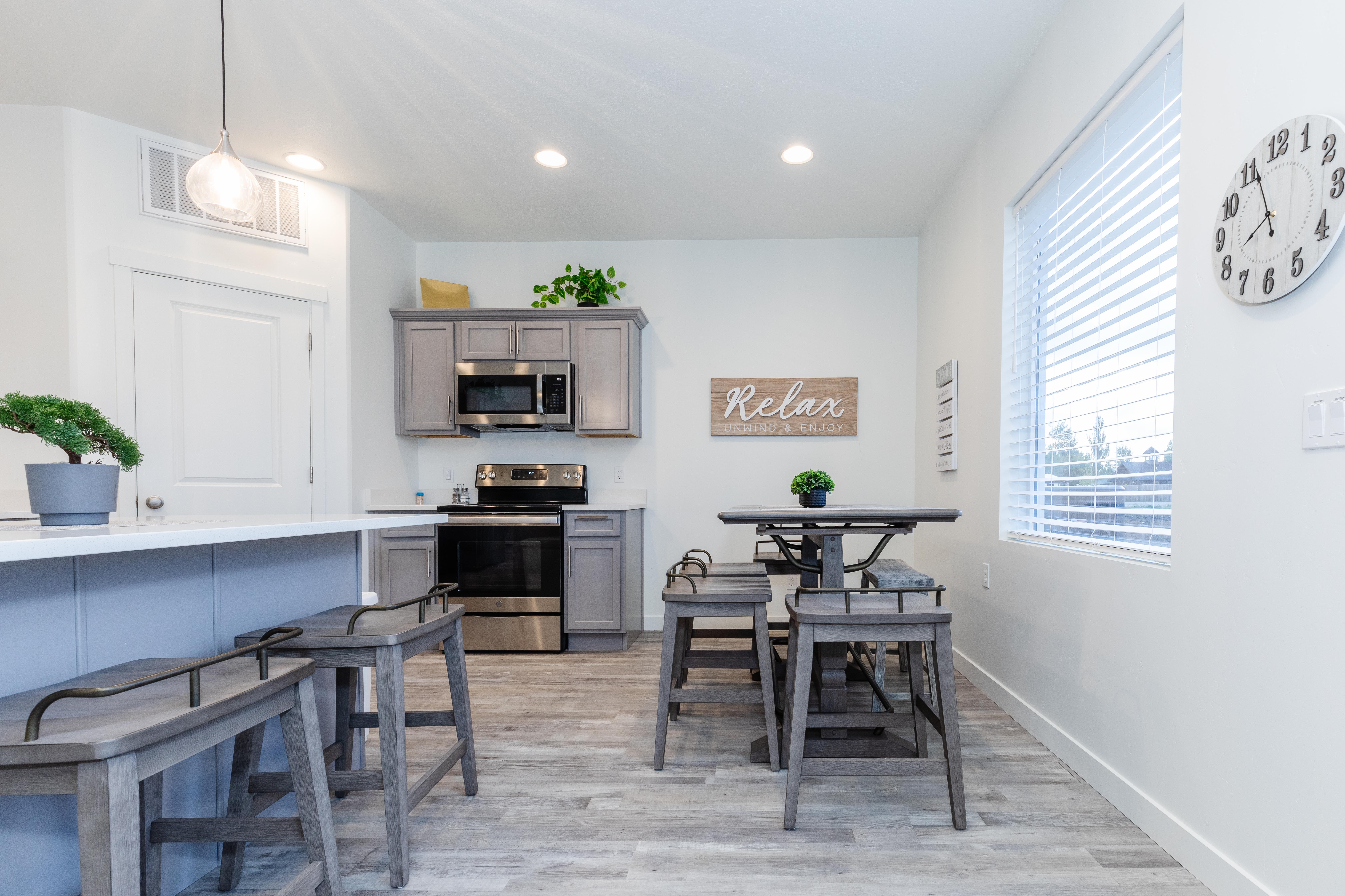 Contemporary kitchen featuring light gray cabinetry, stainless steel appliances, and wood-finish flooring