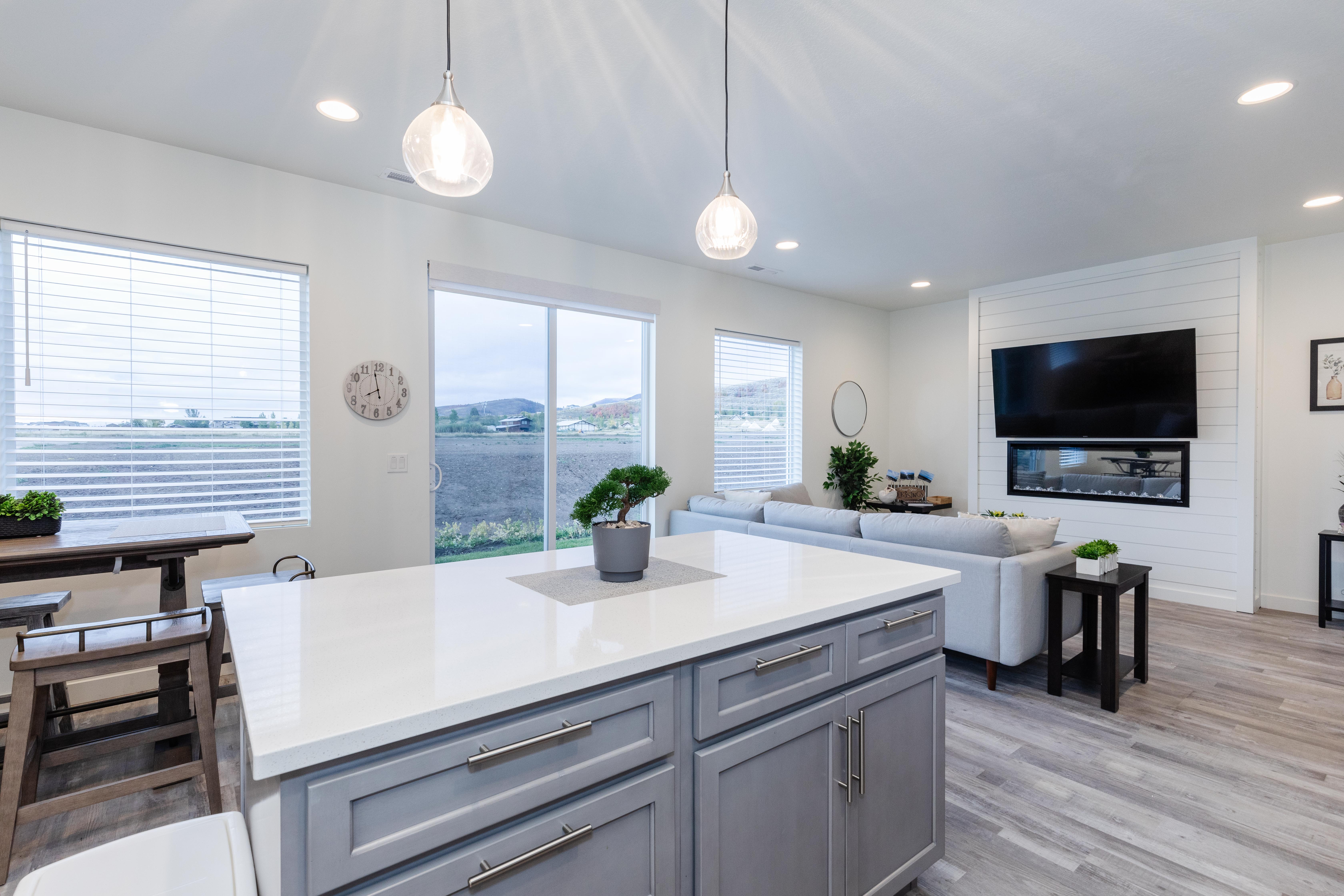 Open-concept living space featuring a gray kitchen island with white countertop, recessed lighting, and wood-finish flooring