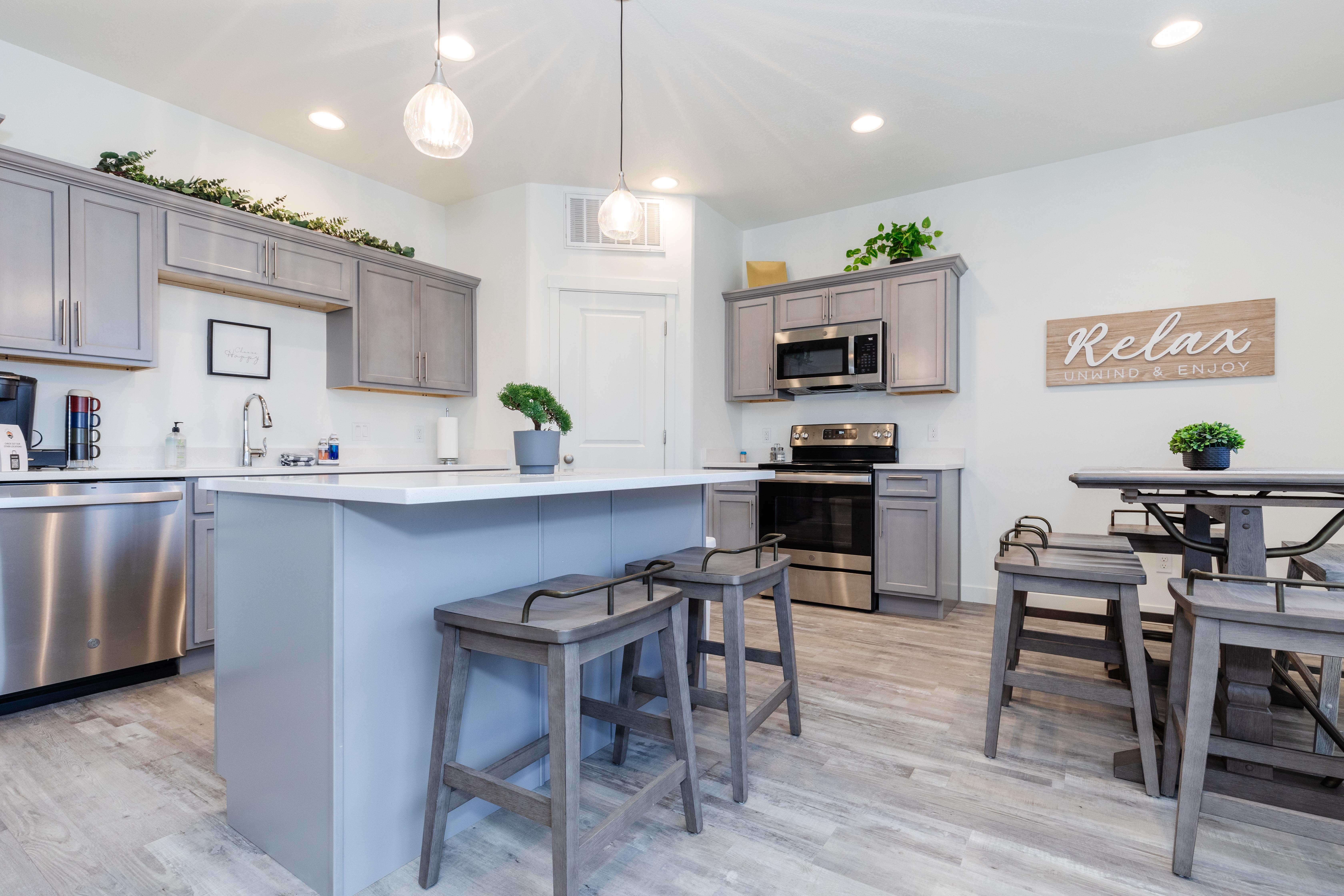 Contemporary kitchen featuring a central island, light gray cabinetry, stainless steel appliances, recessed lighting, and wood-finish flooring