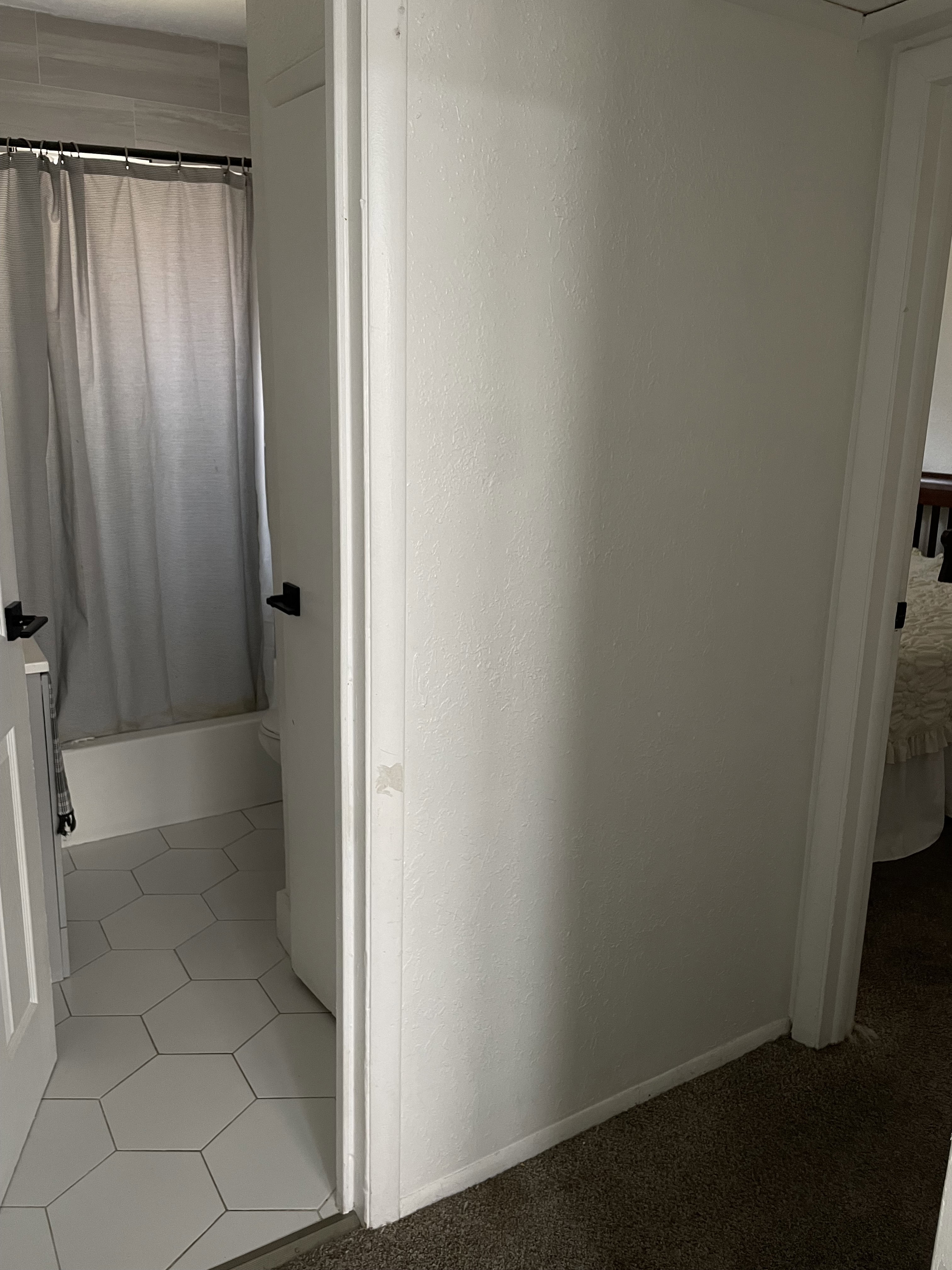 Bathroom featuring white hexagonal floor tiles, a white bathtub, and light grey wall tiles