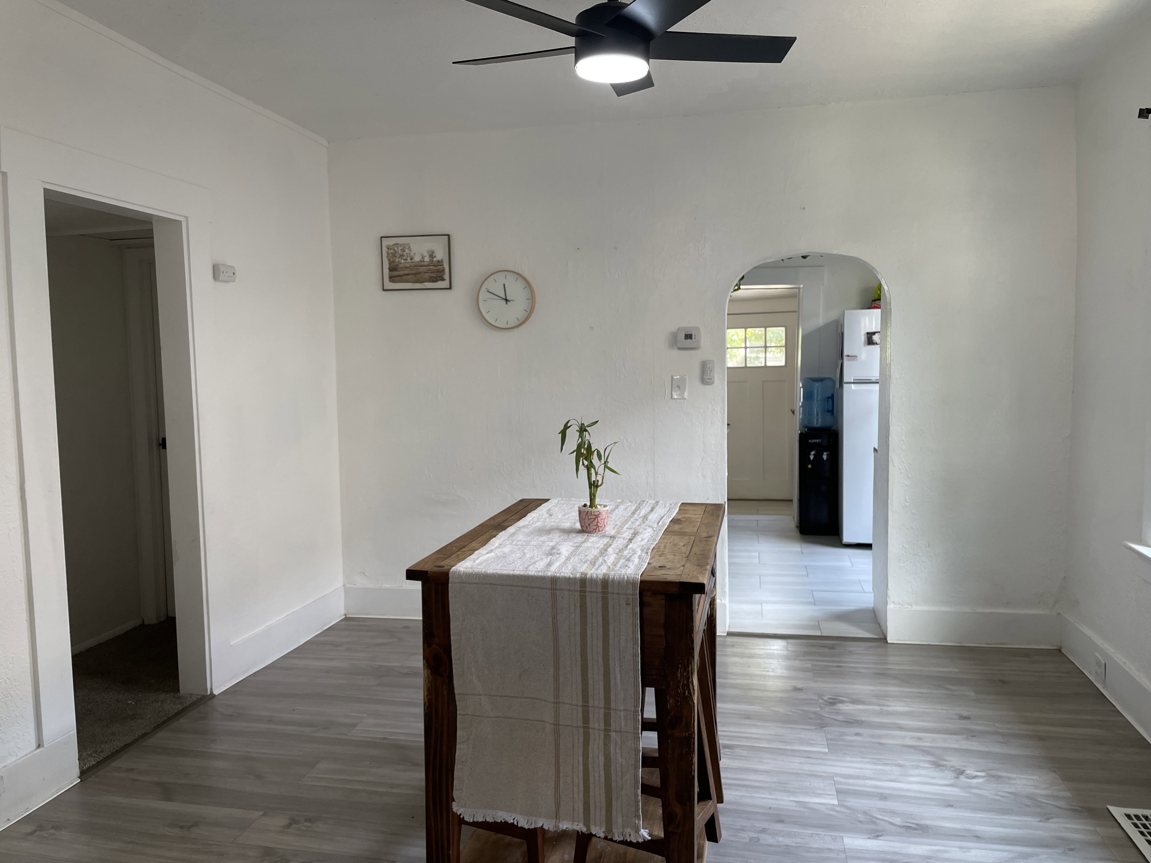 Interior space with wood-finish flooring and a contemporary black ceiling fan with integrated lighting