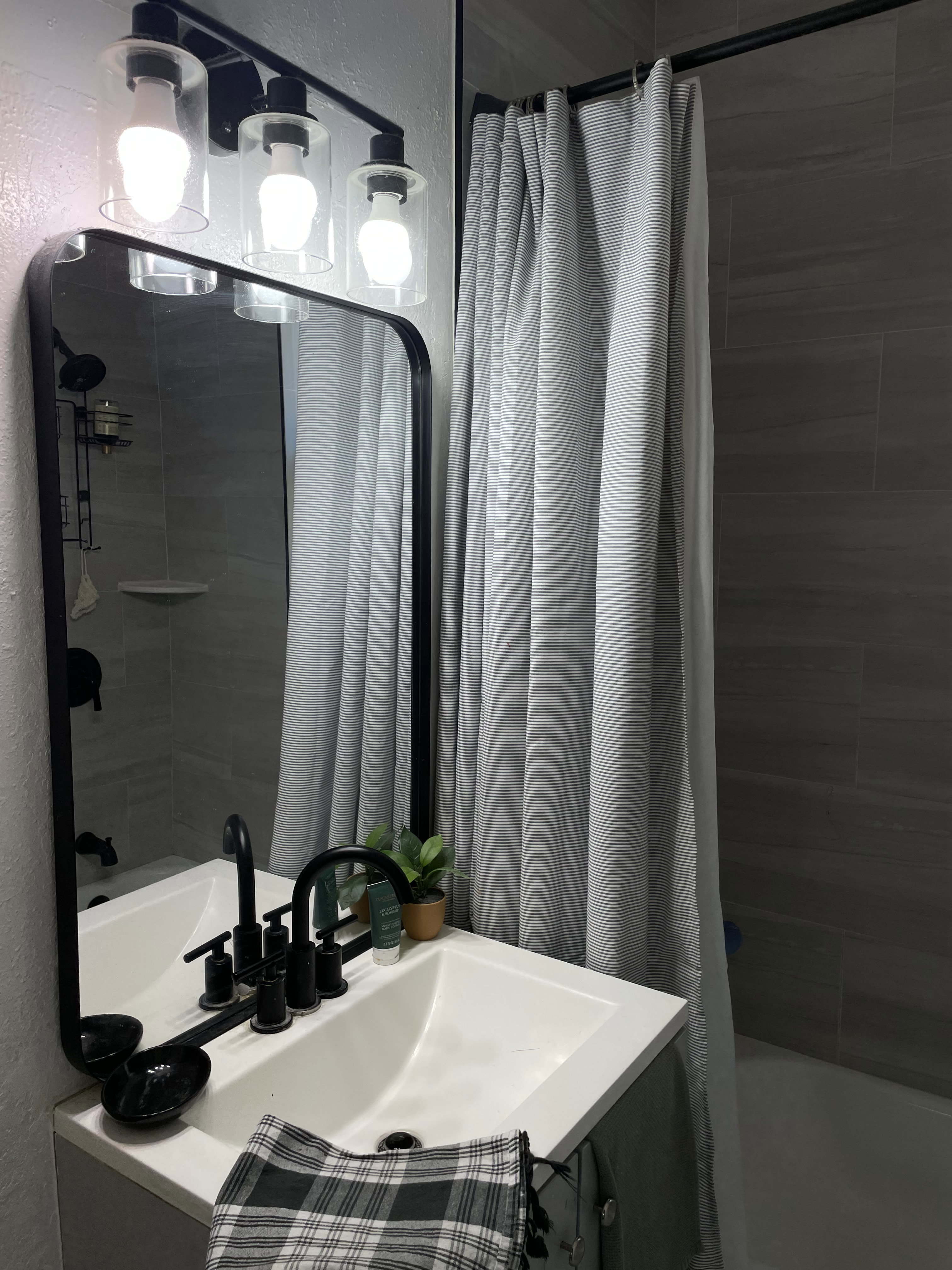 Bathroom featuring a white vanity with integrated sink, matte black faucet, and rectangular mirror