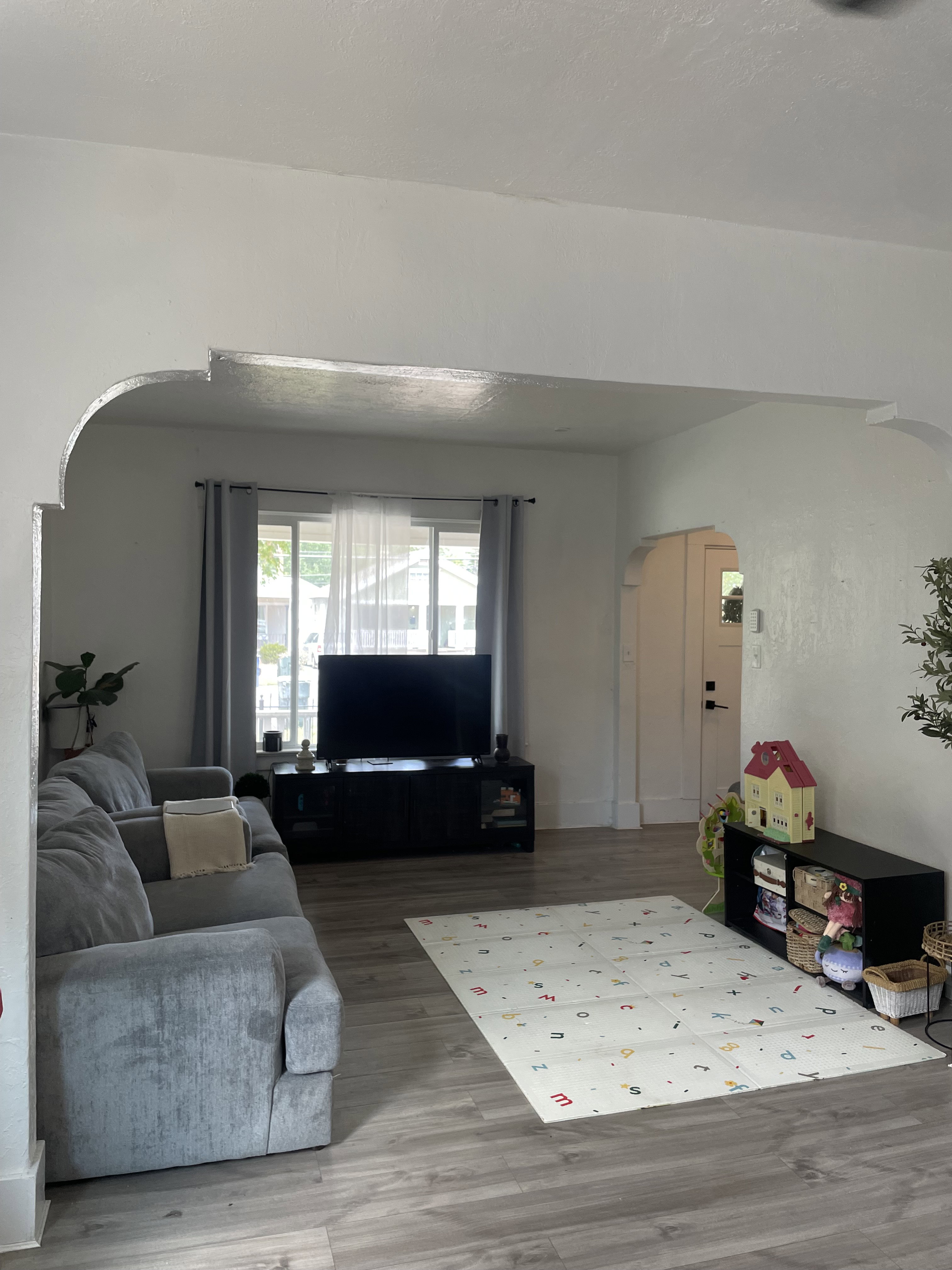 Expansive living area featuring arched doorways, wood-finish flooring, and white baseboards