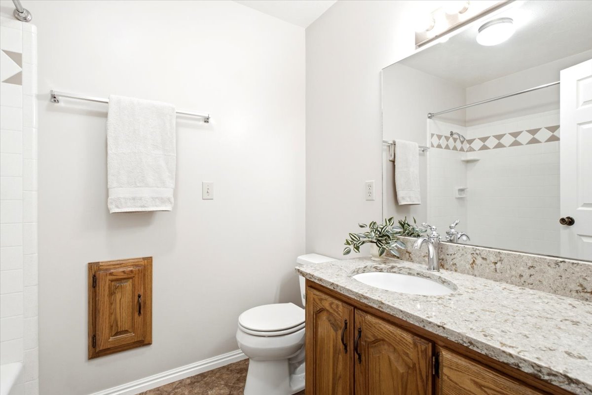 Main bathroom with updated quartz countertop, tile surround and cast iron tub