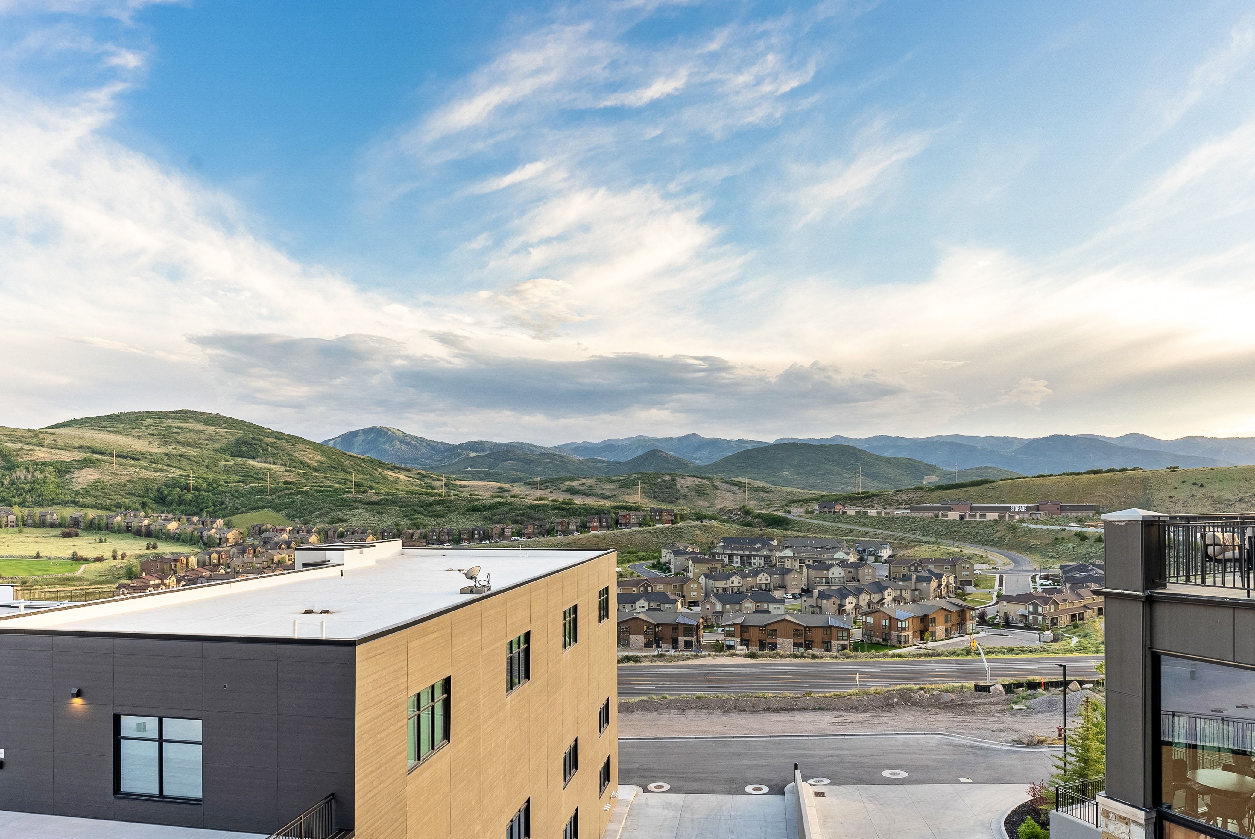 Expansive mountain landscape featuring distant residential developments and a contemporary building with a flat roof and a partial balcony