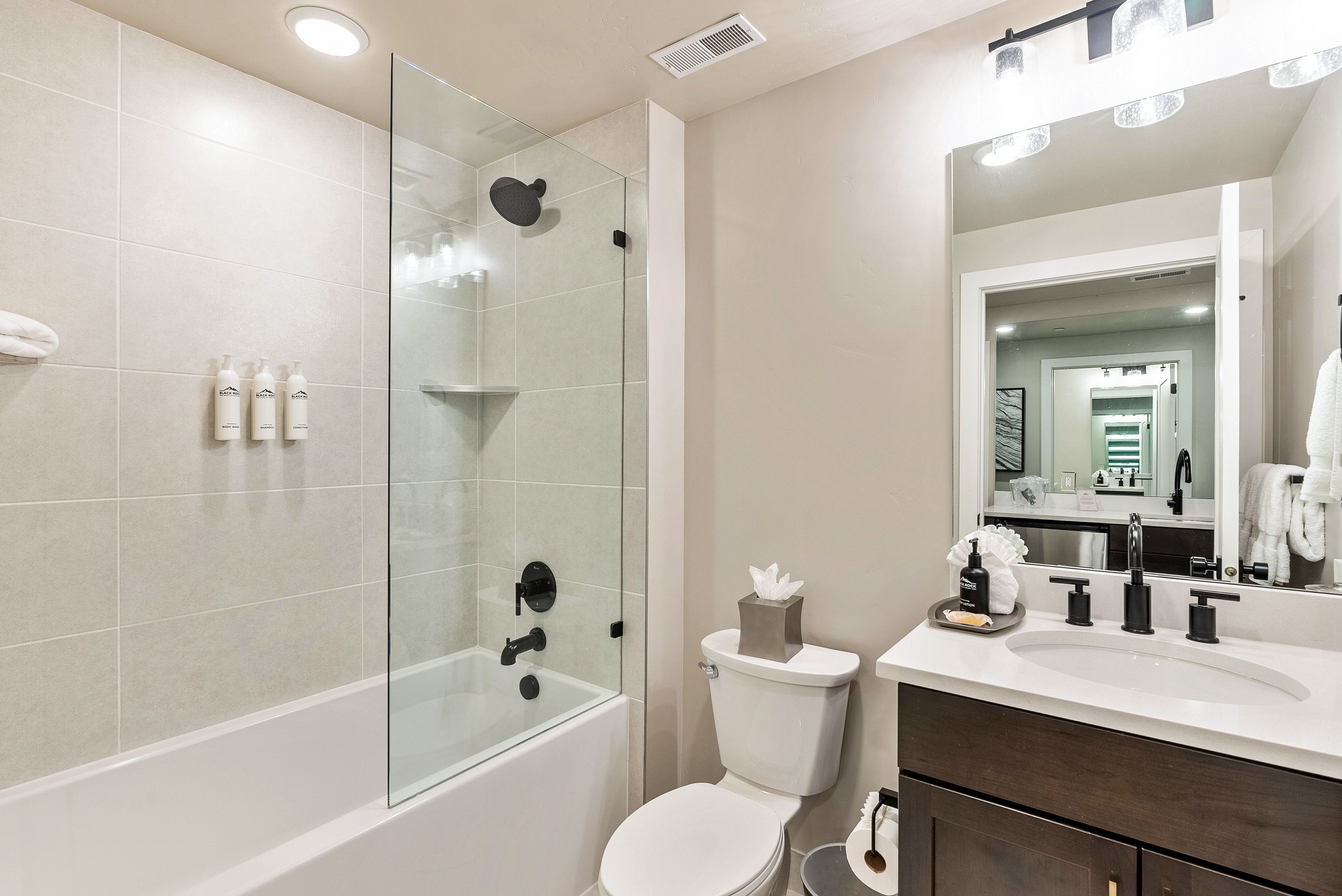 Bathroom featuring a tub/shower combination with a clear glass enclosure and matte black fixtures