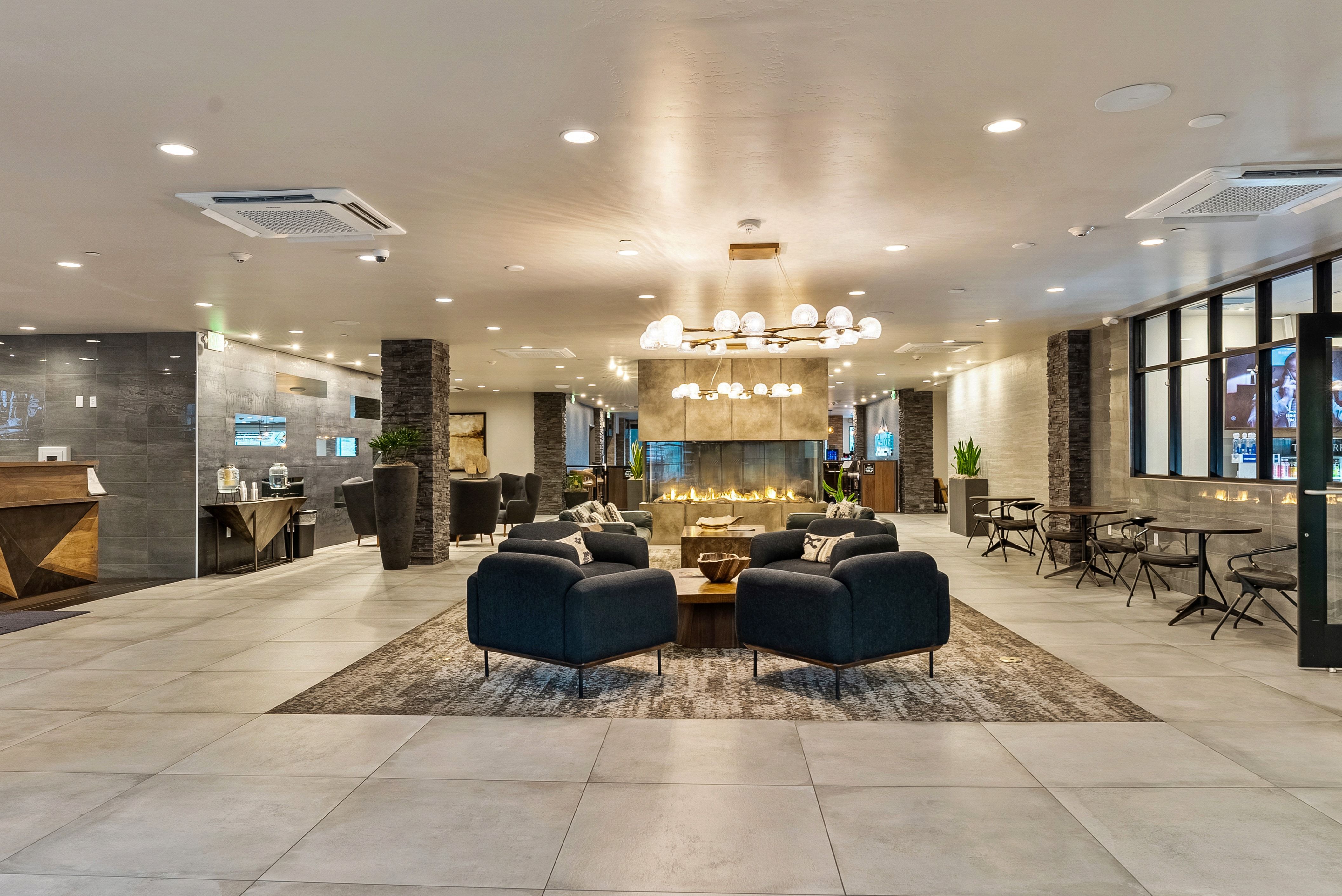 Spacious common area featuring large format tile flooring, a central linear fireplace, and integrated recessed lighting