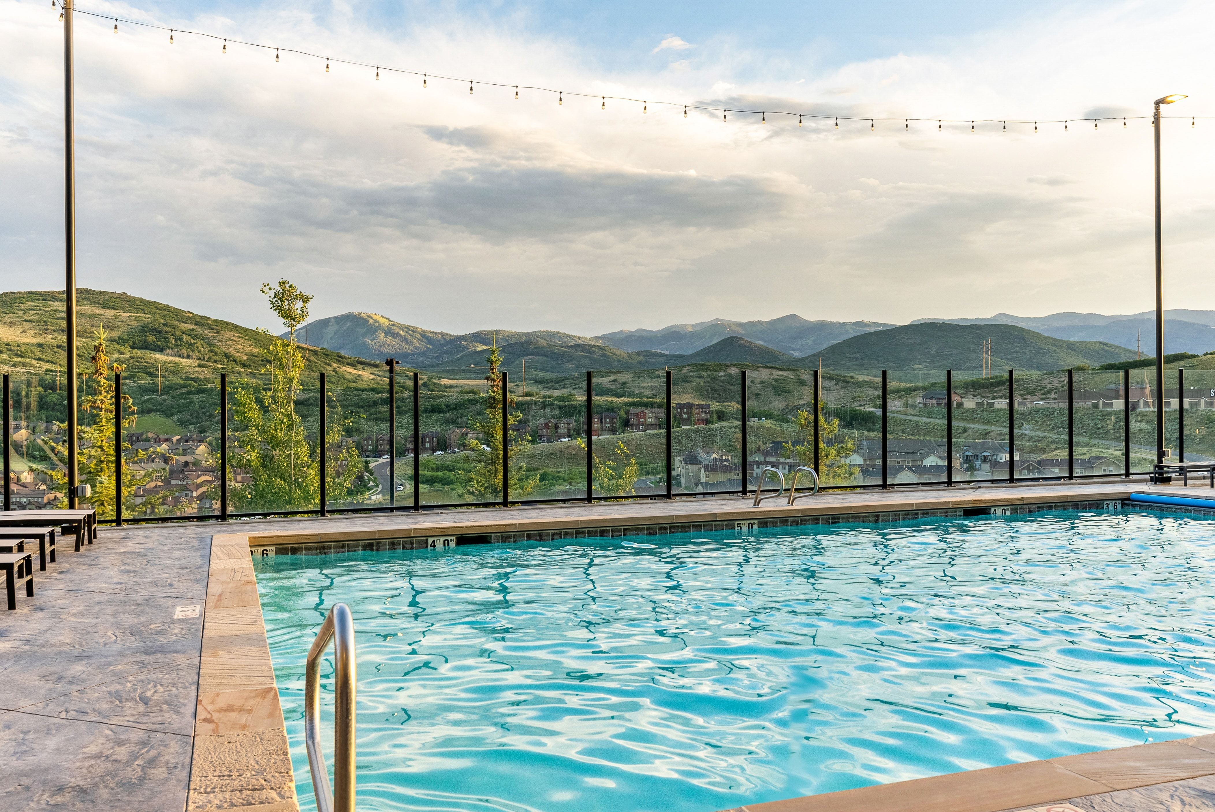 Outdoor swimming pool with a stainless steel handrail, stone coping, and textured concrete decking