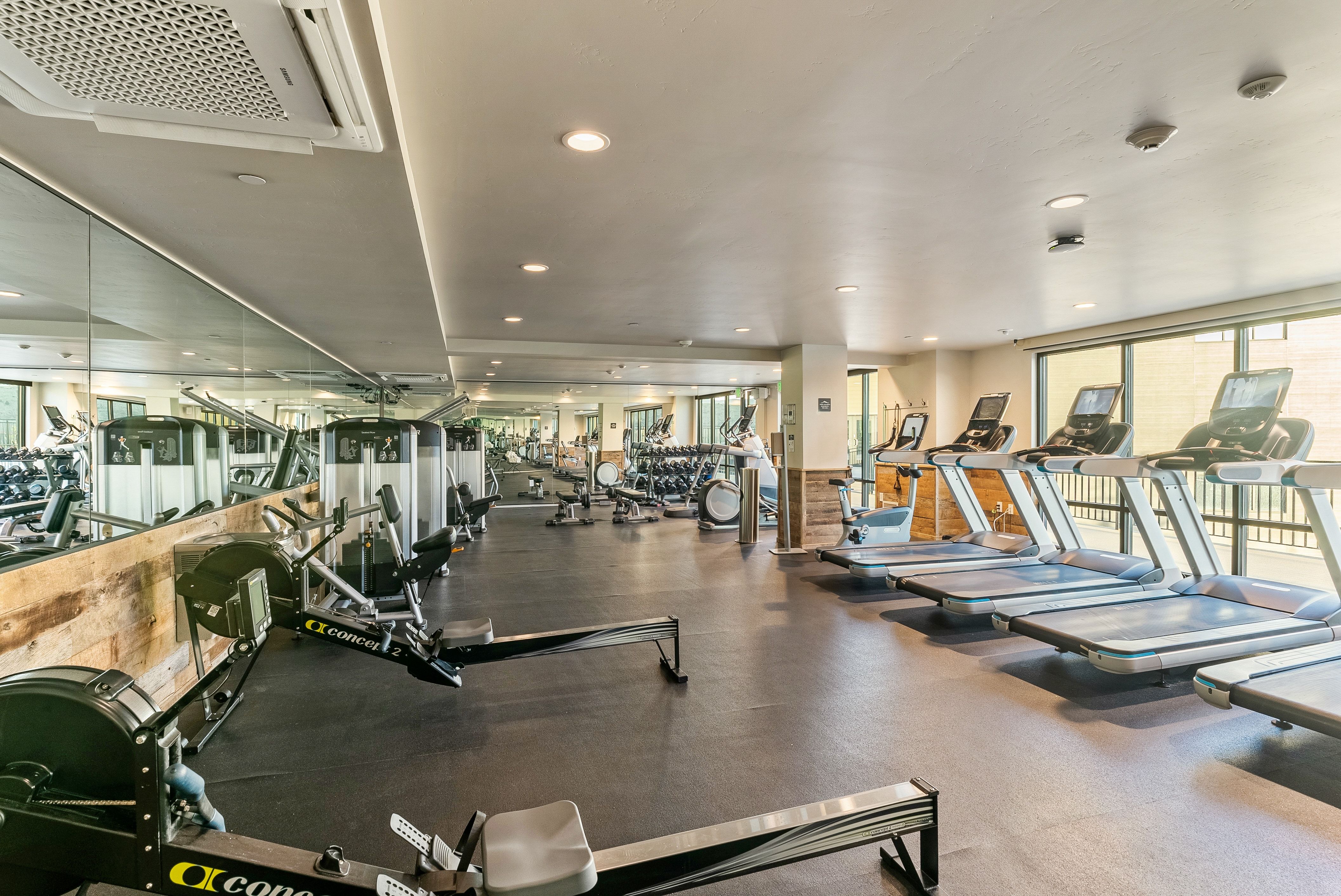 Dedicated fitness center featuring extensive mirrored walls, recessed lighting, and a rubber flooring system