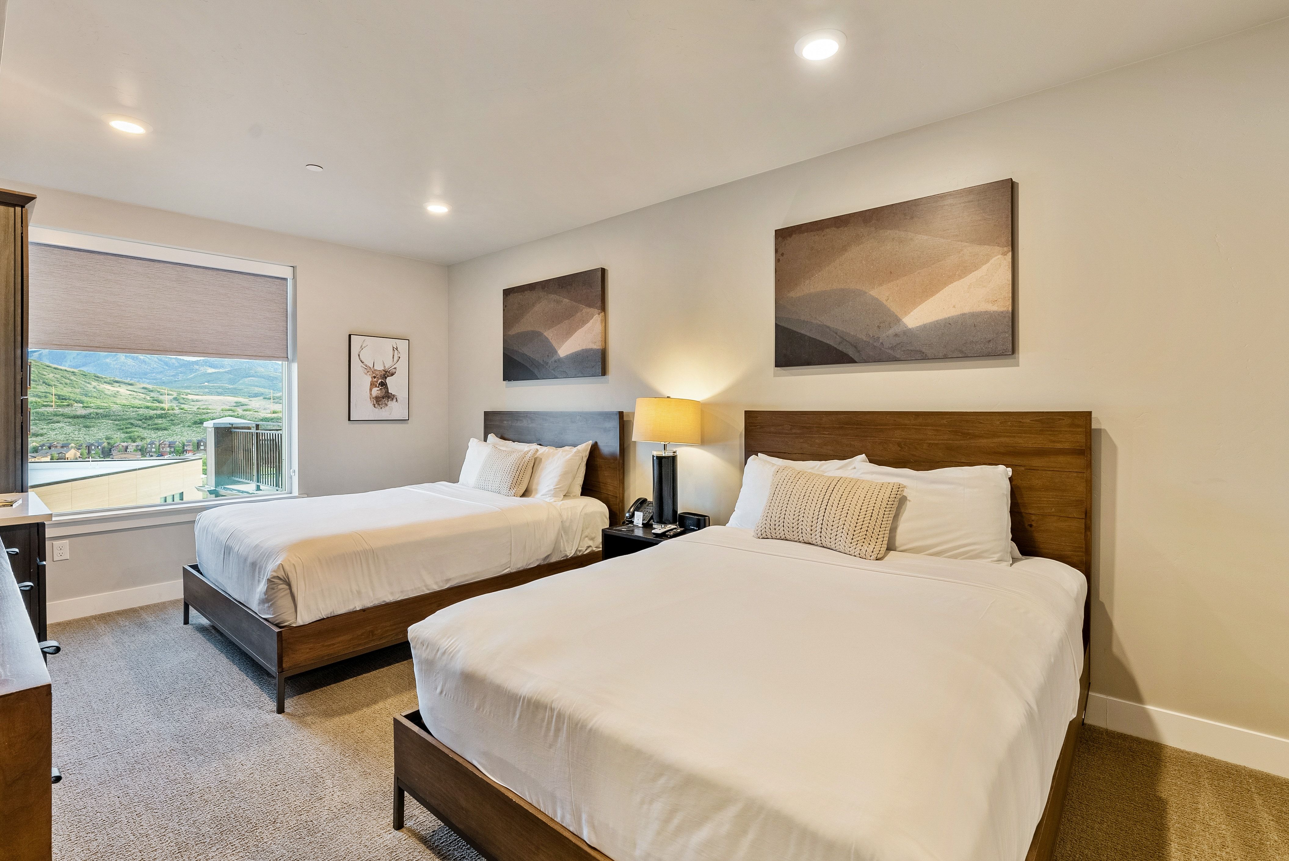 Bedroom featuring two wood-frame beds, a large window with roller shades, recessed lighting, and soft carpet flooring