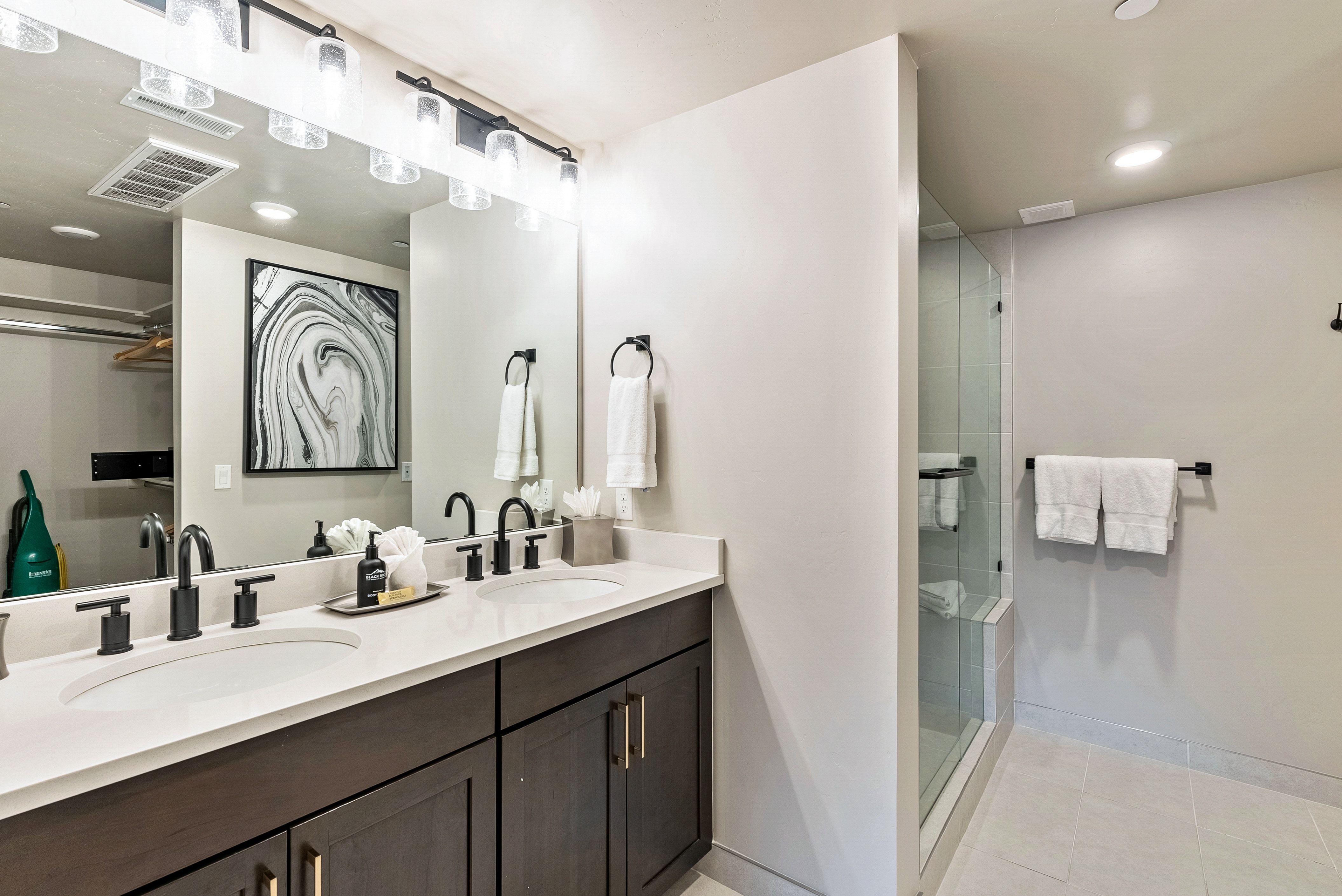 Dual vanity with dark wood-finish cabinetry, white countertop, and matte black fixtures