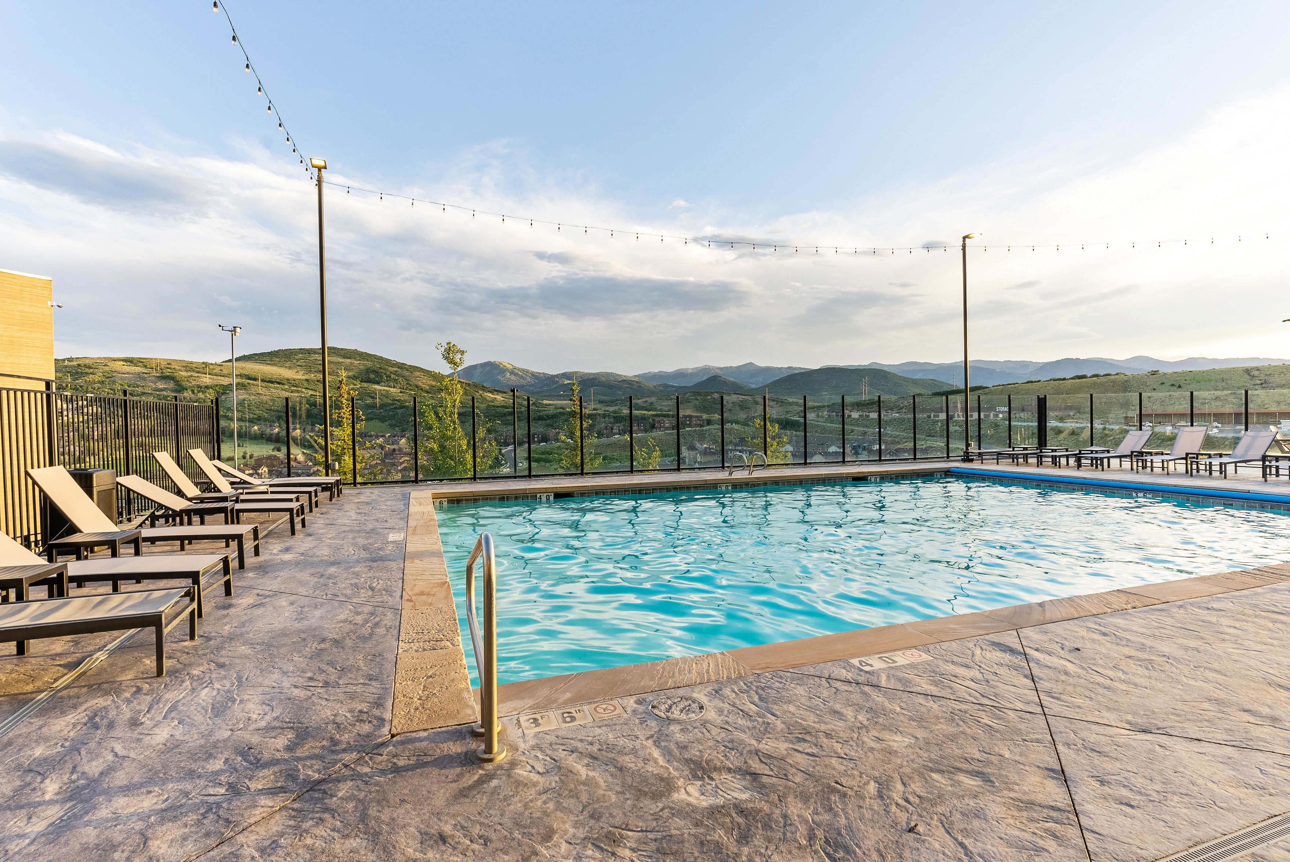 Outdoor swimming pool with stamped concrete decking and surrounding black metal fencing