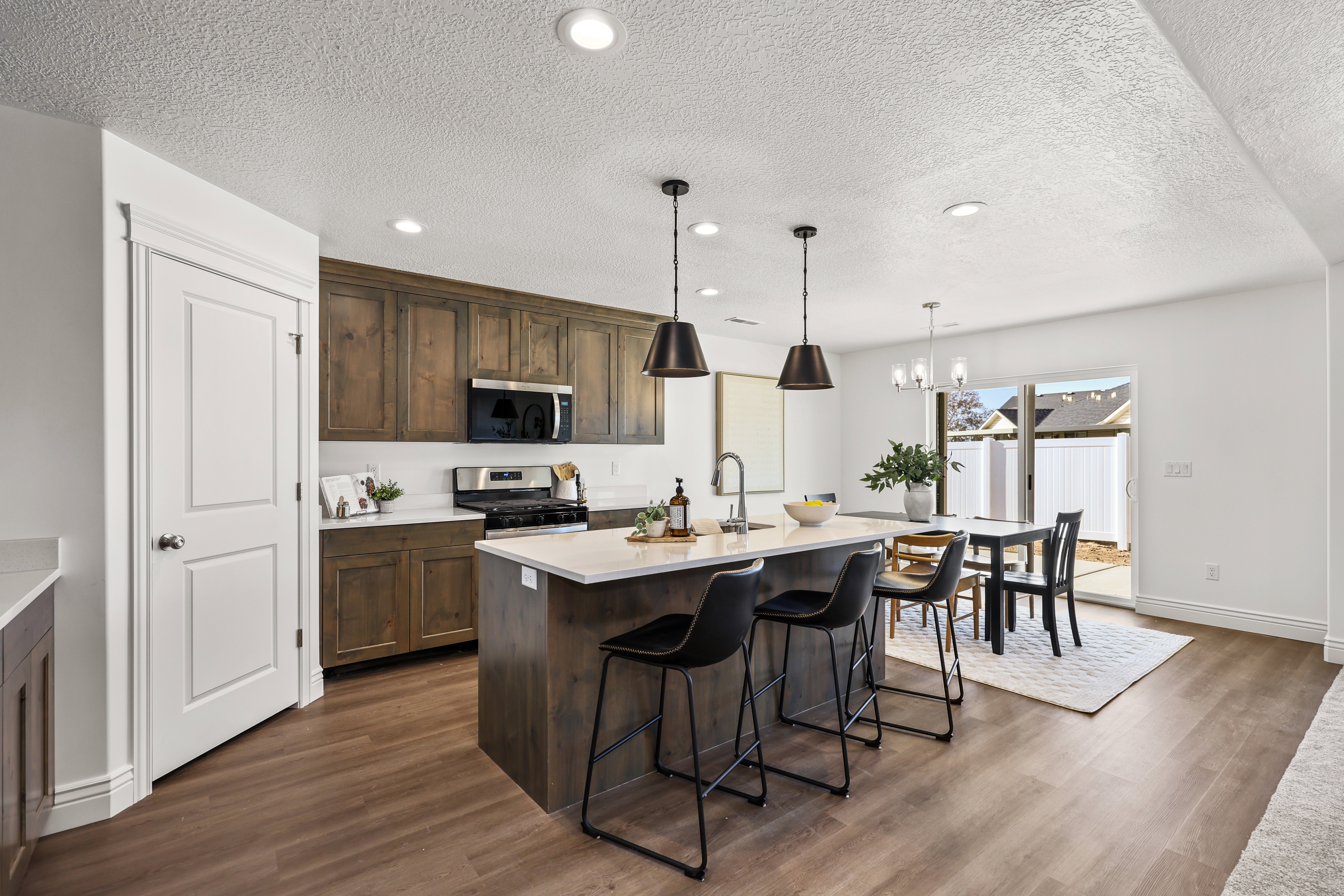 Open-concept kitchen featuring wood-finish flooring, a central island with countertop seating, stainless steel appliances, and wood cabinetry