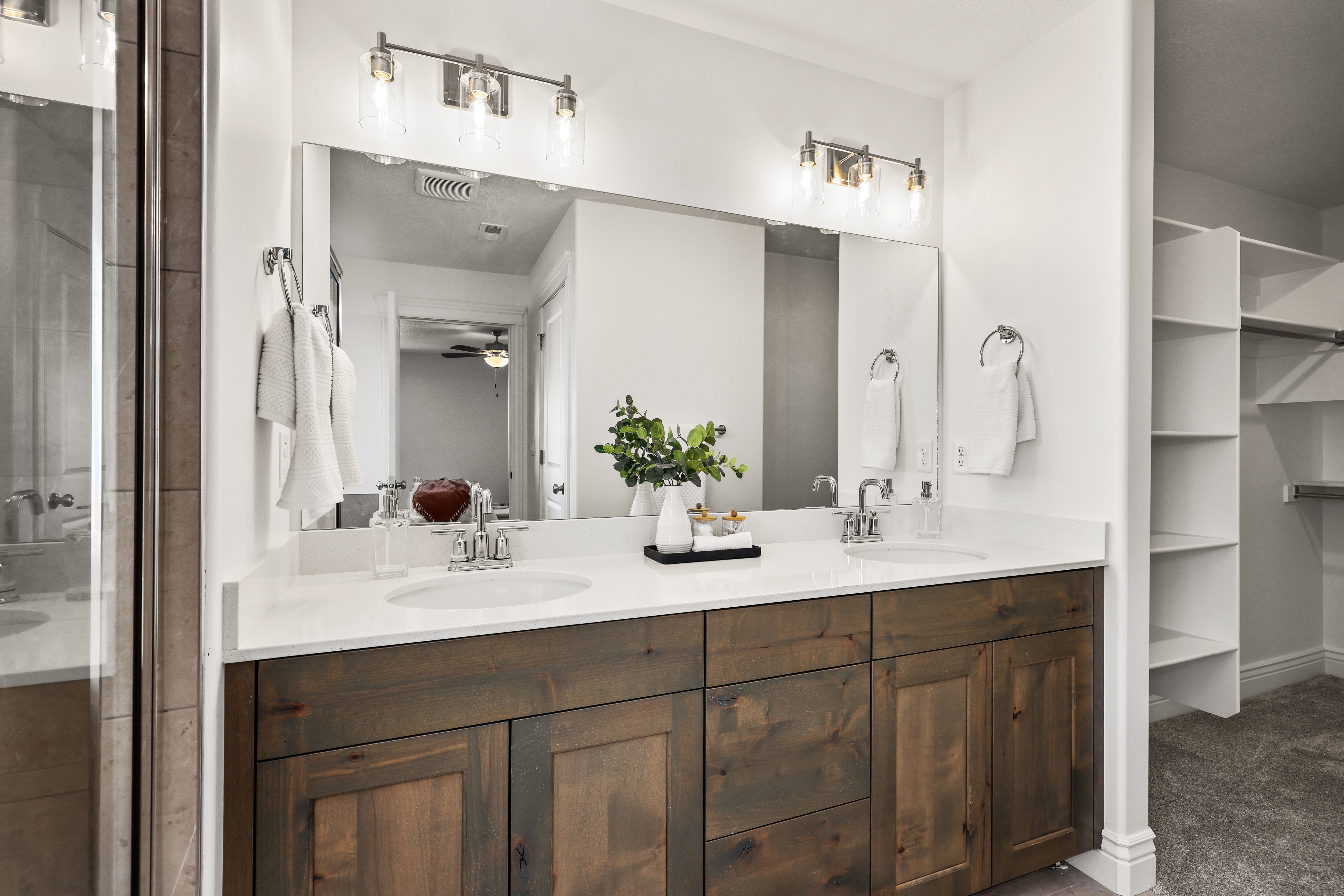 Double vanity with wood-finish cabinetry, white countertops, and dual undermount sinks