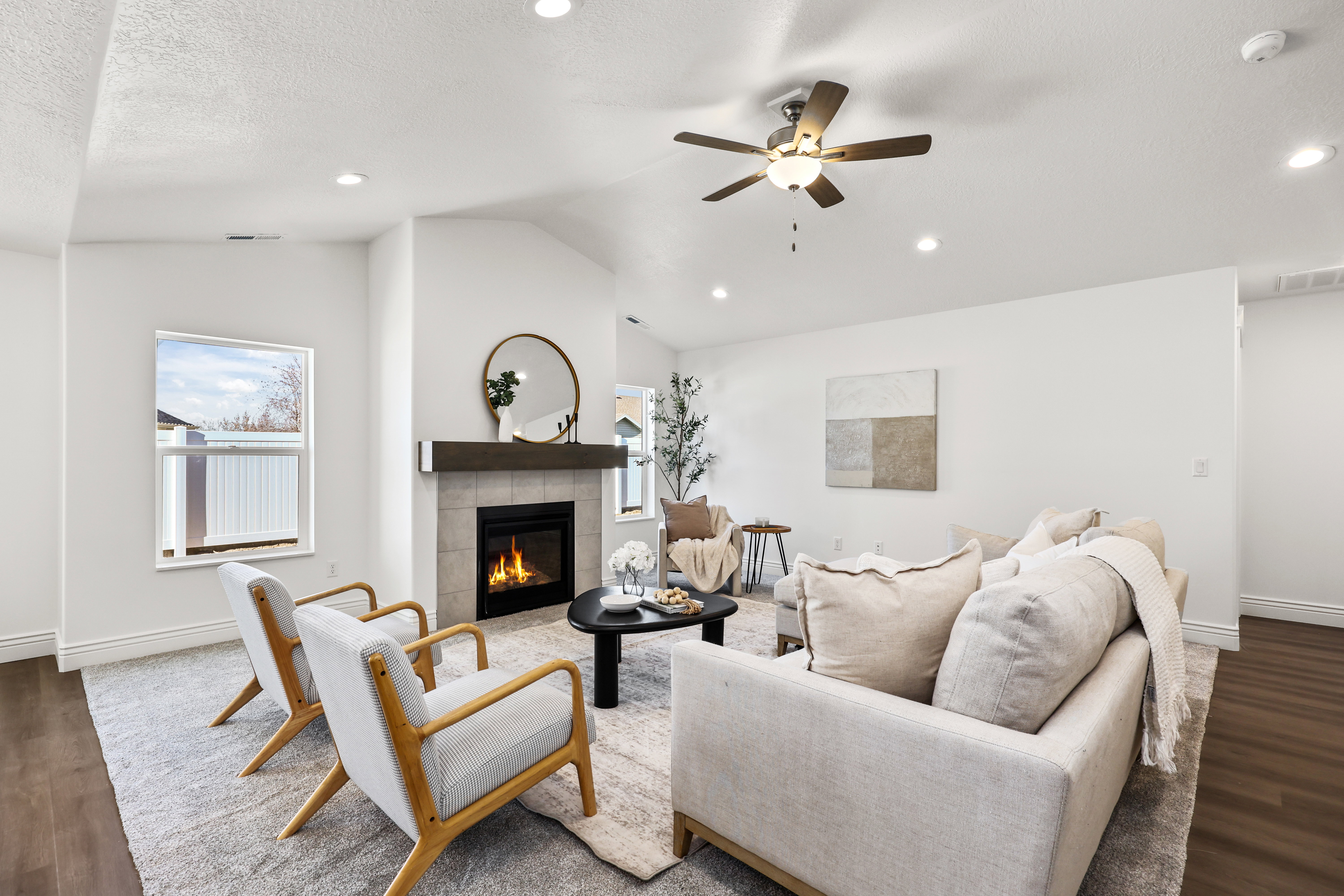 Living area featuring a floor-to-ceiling tiled fireplace with a wood mantel, vaulted ceiling, recessed lighting, ceiling fan, and wood-finish flooring