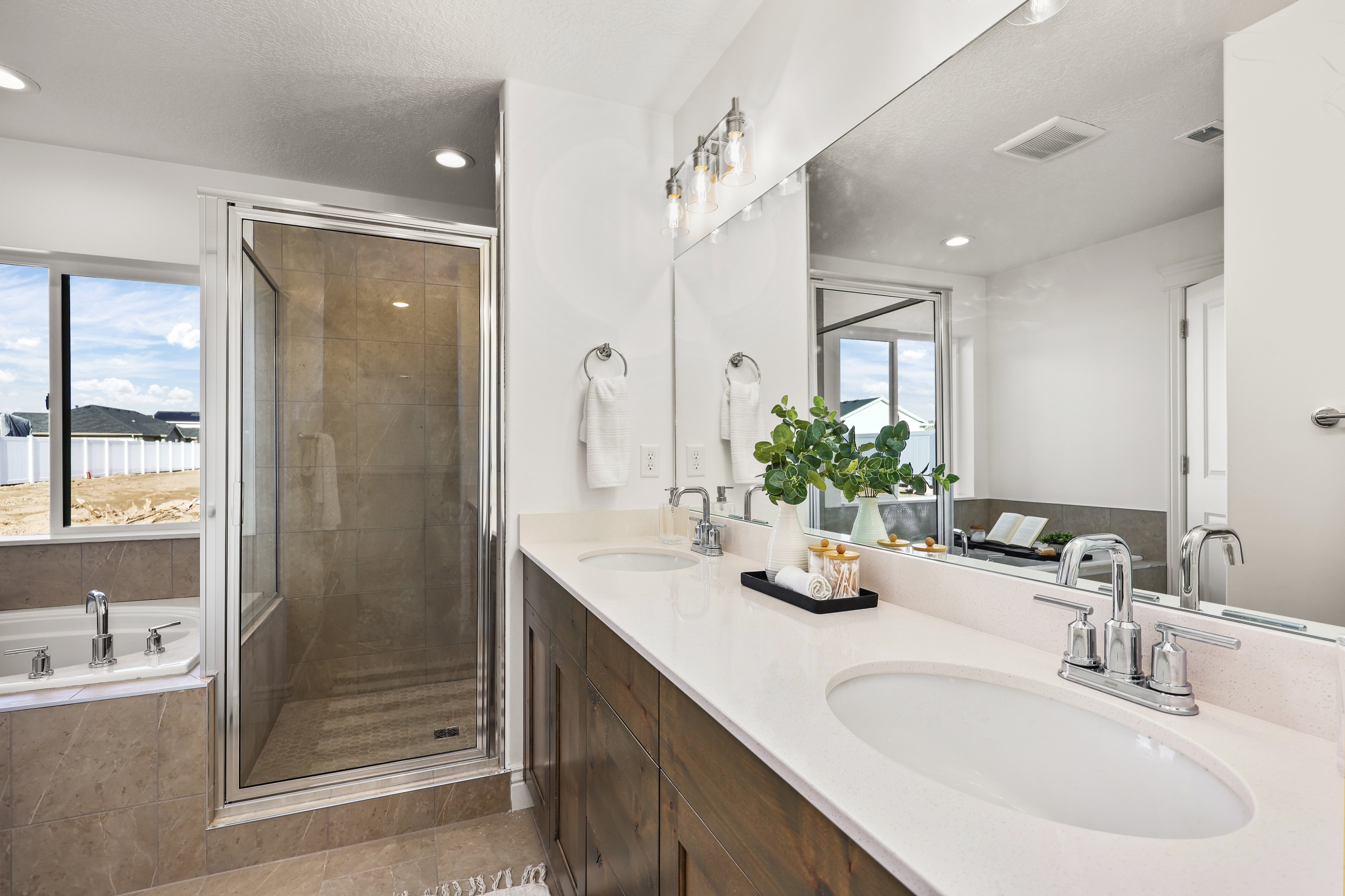 Bathroom featuring a dual vanity with undermount sinks, a walk-in shower with a glass enclosure, a built-in soaking tub, and recessed lighting