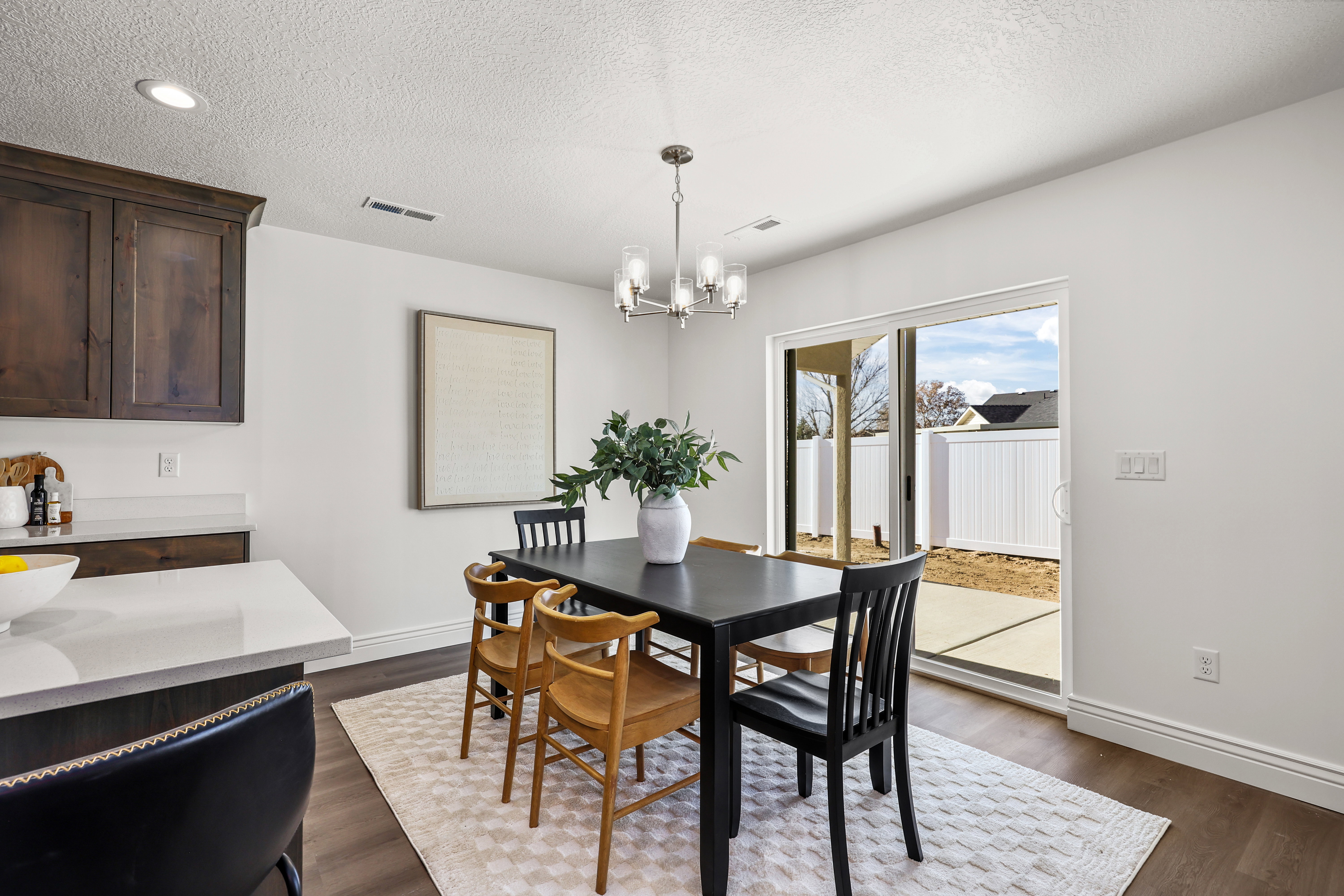 Open concept dining area featuring wood-finish flooring, a contemporary chandelier, and bright white walls