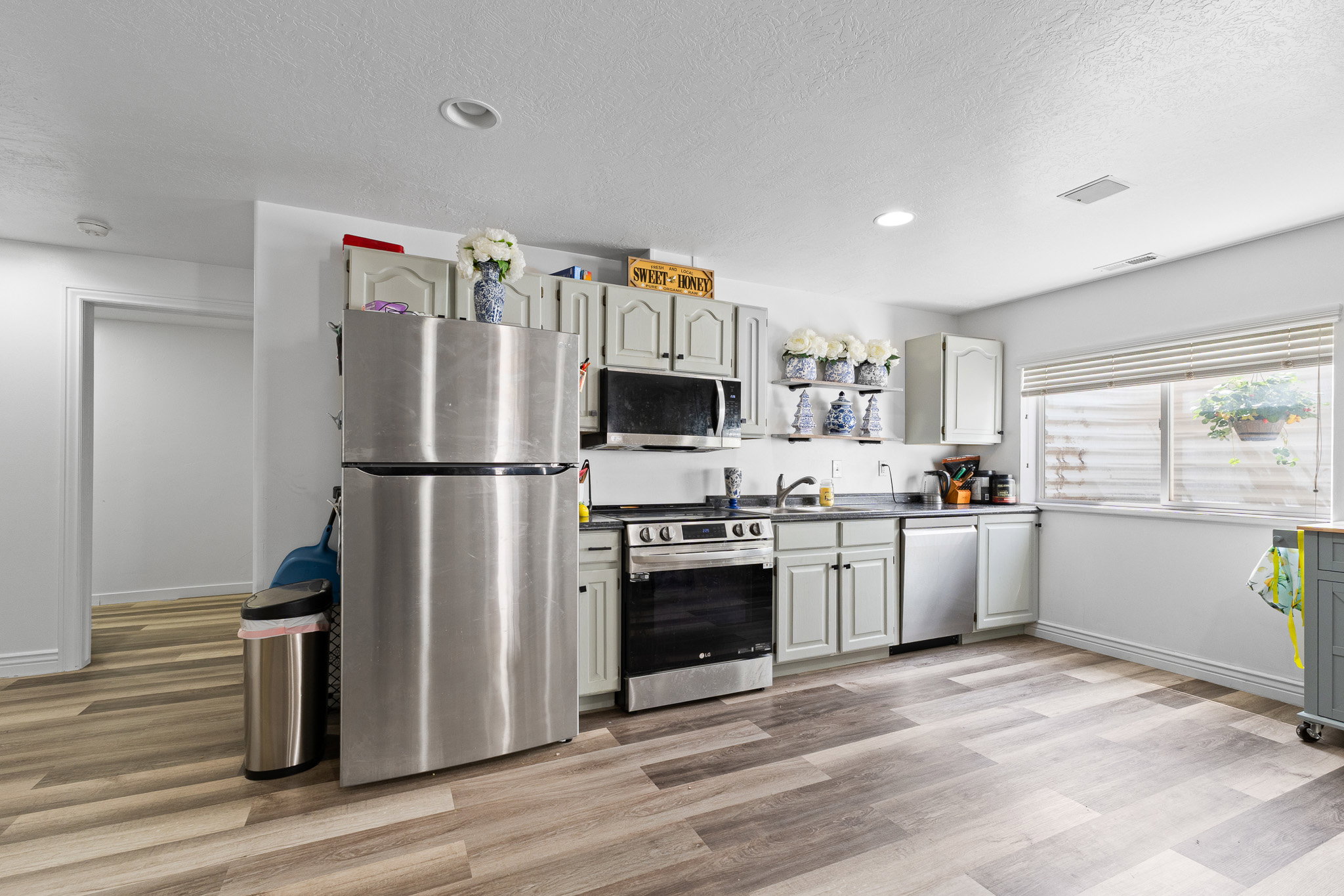 Kitchen featuring wood-finish flooring, recessed lighting, light-toned cabinetry, stainless steel appliances, and a window with blinds