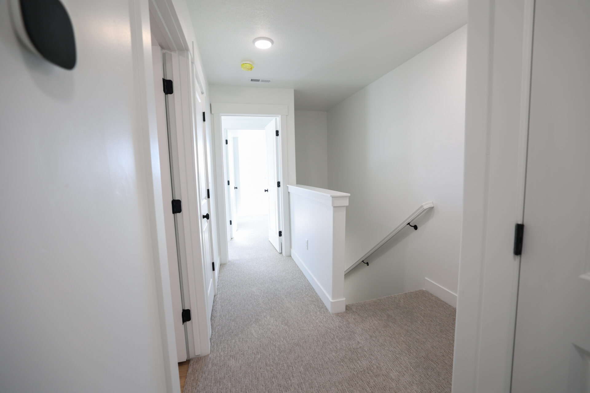 Bright hallway featuring light-colored carpeting and white walls