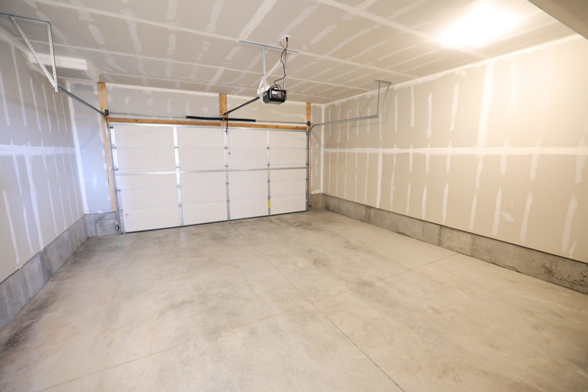 Spacious garage featuring a concrete floor, an overhead garage door, and an automatic garage door opener