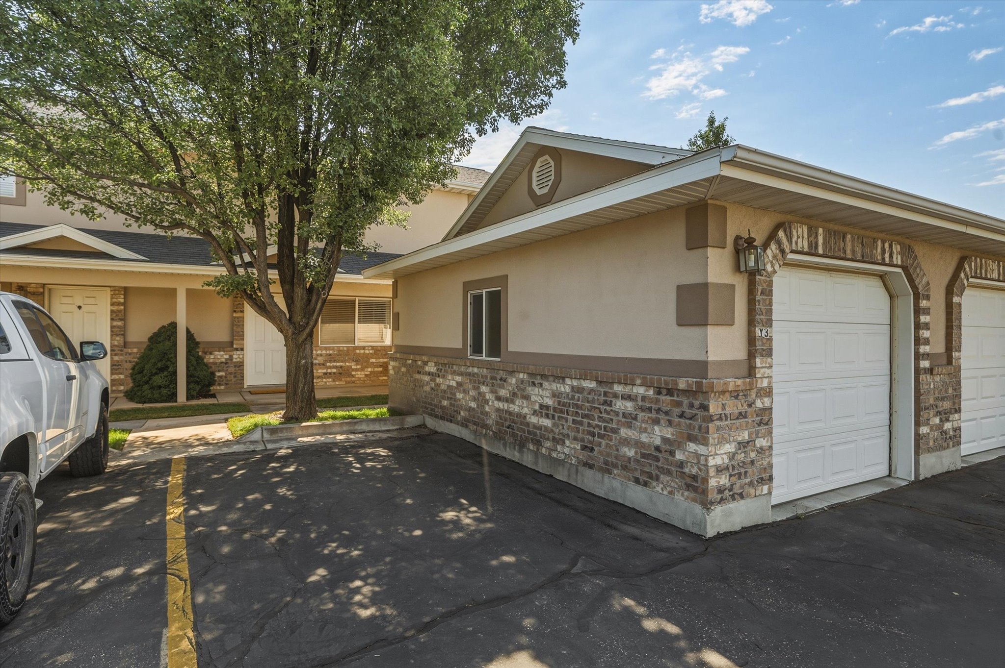 Exterior featuring a brick and stucco facade, attached garage with arched brick detailing, and a front entry porch