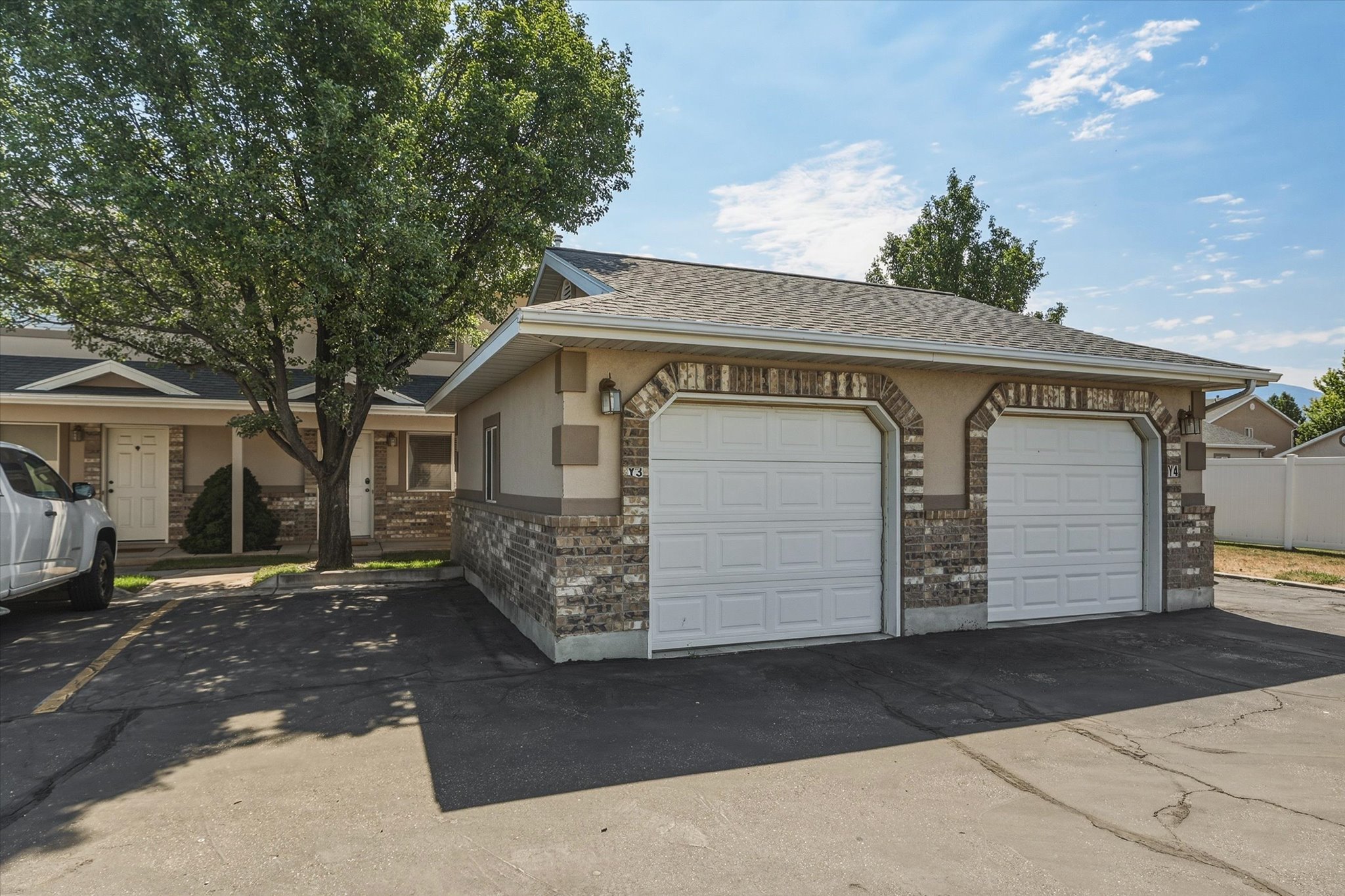 Two-car garage with arched brick detailing, stucco siding, and complementary outdoor lighting fixtures