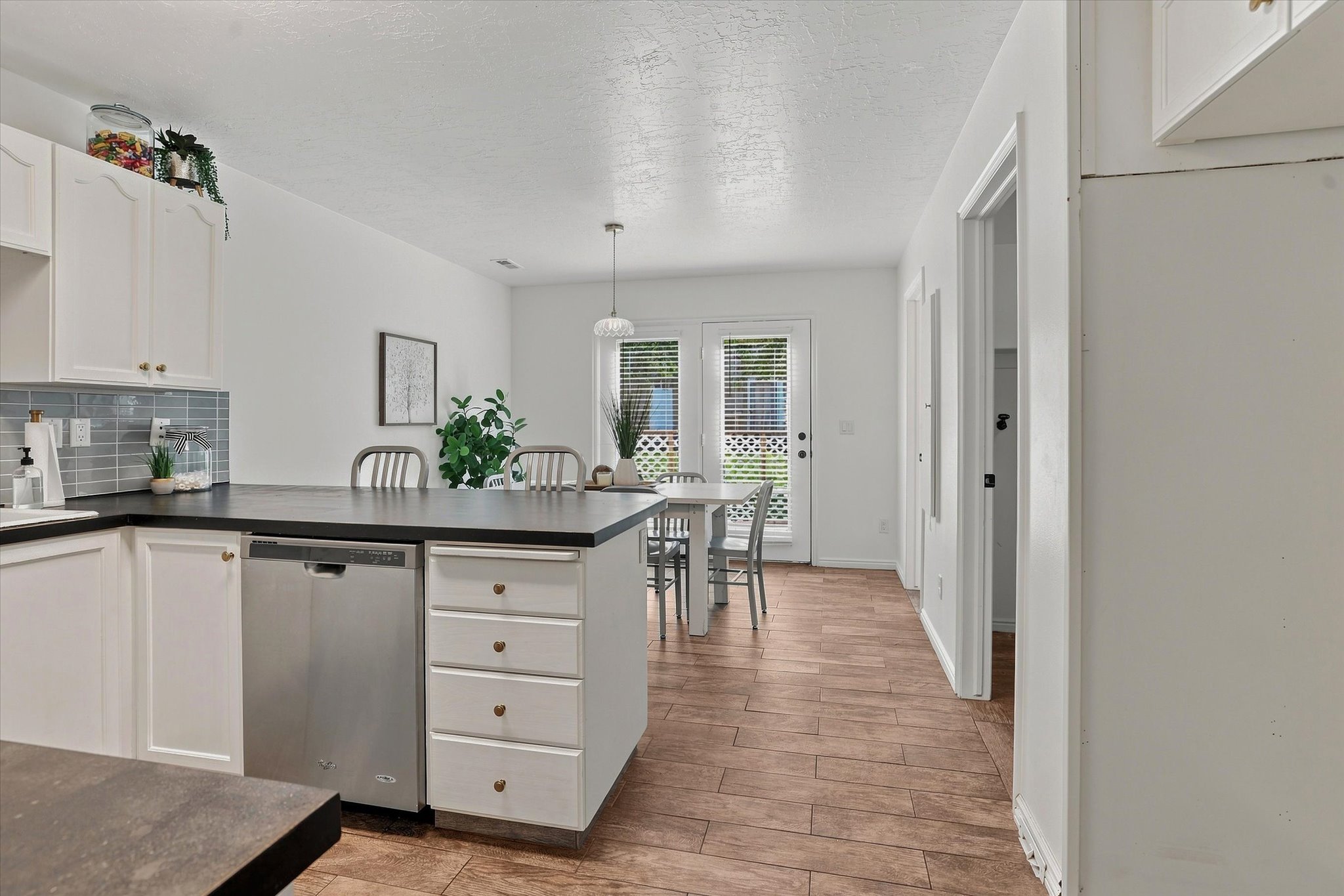 Kitchen featuring white cabinetry, dark countertops, a tile backsplash, and stainless steel appliances