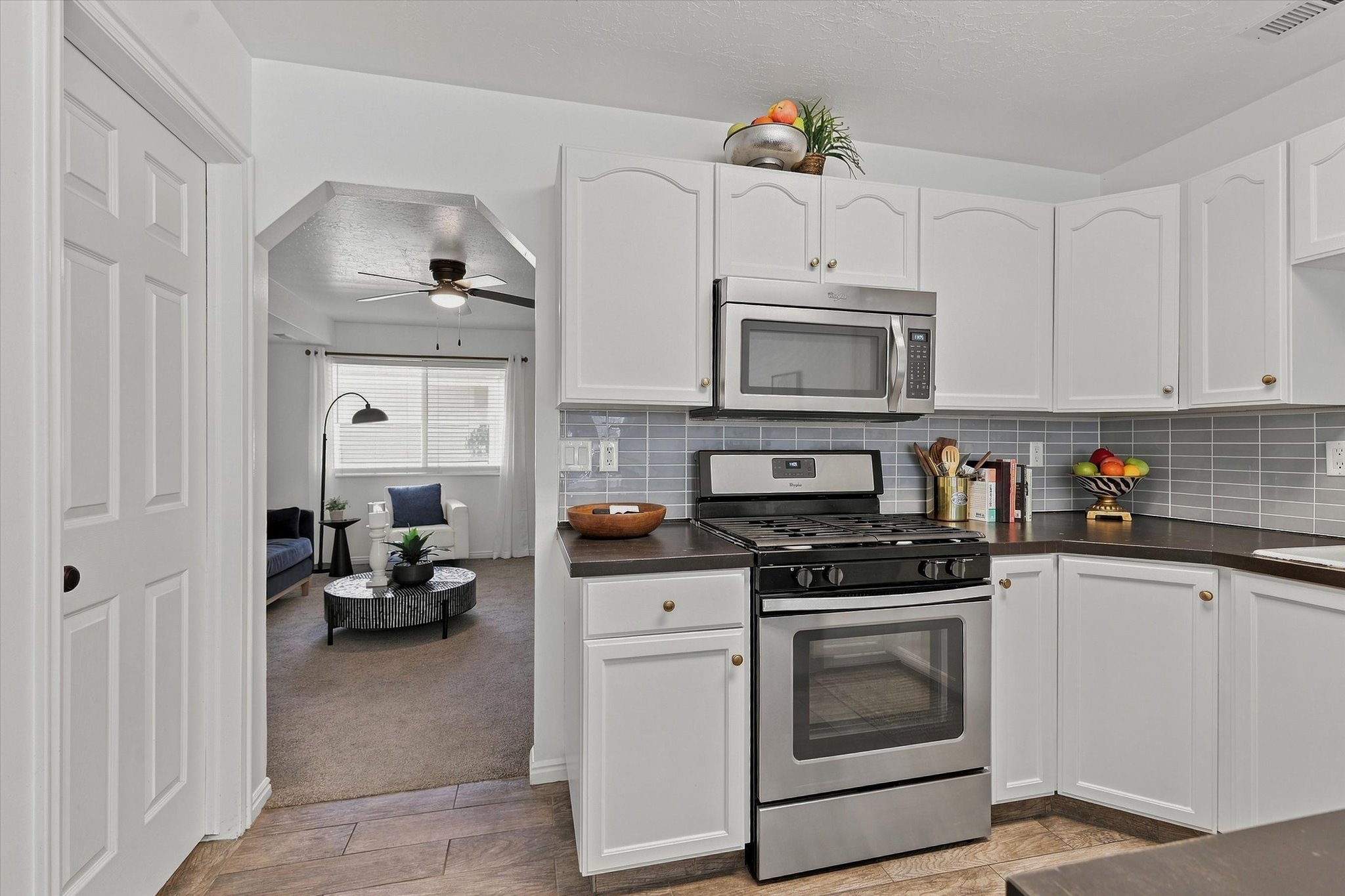 Kitchen featuring white cabinetry, stainless steel appliances, dark countertops, and a gray subway tile backsplash